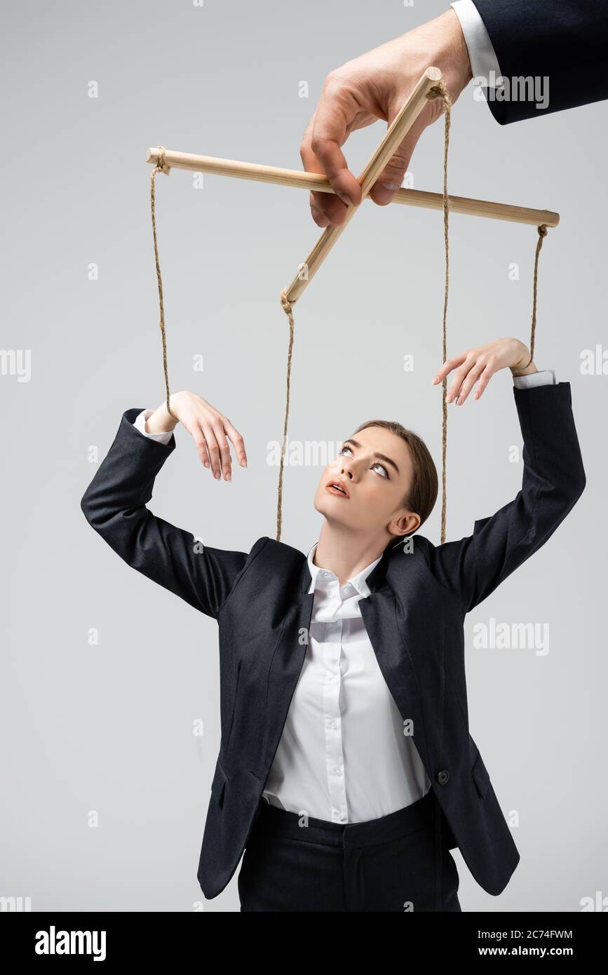 cropped view of puppeteer holding businesswoman marionette on strings  isolated on grey Stock Photo - Alamy