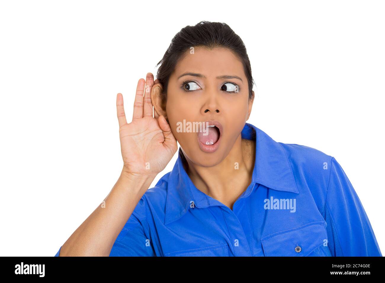 Portrait of a nosy shocked woman with hand to ear gesture listening to a gossip conversation Stock Photo