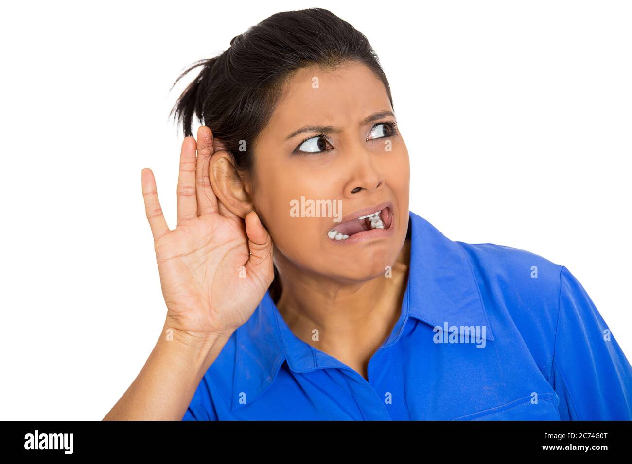 Portrait of a nosy disgusted woman with hand to ear gesture listening to a gossip conversation Stock Photo