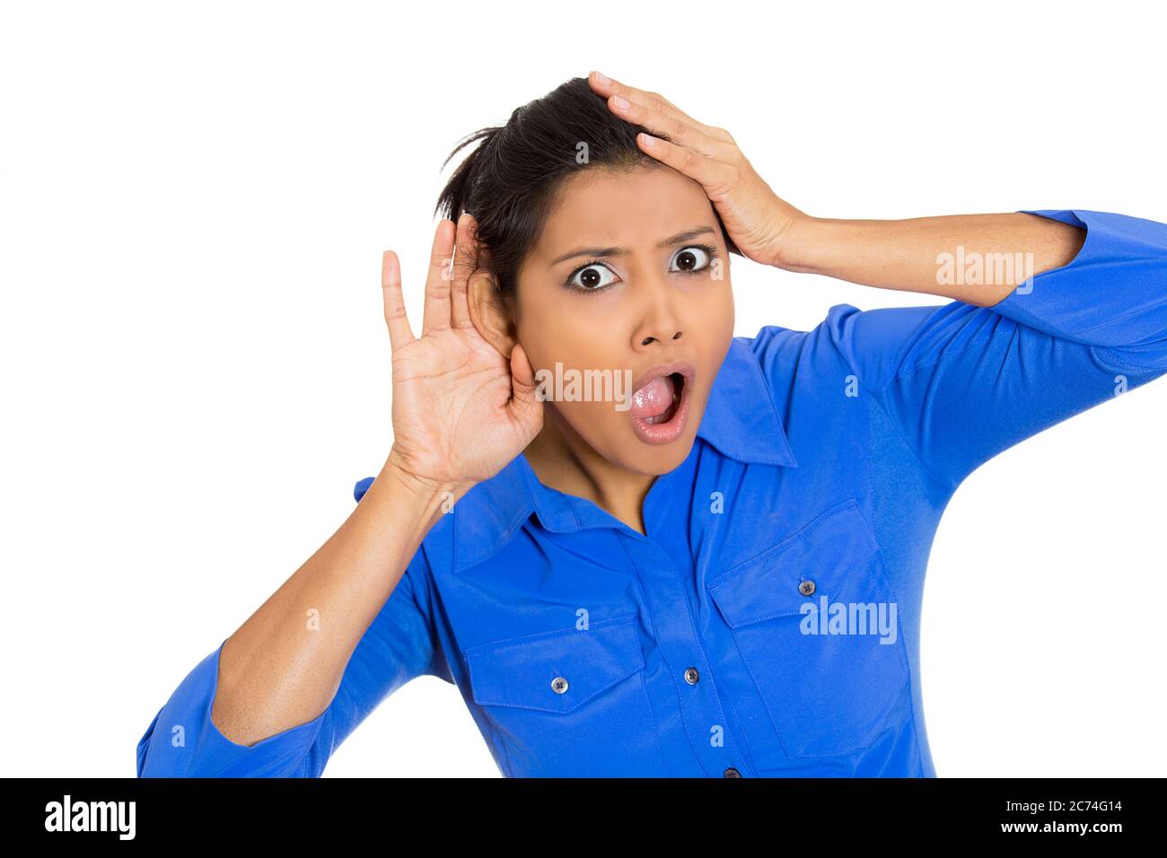 Portrait of a nosy shocked woman with hand to ear gesture listening to a gossip conversation Stock Photo