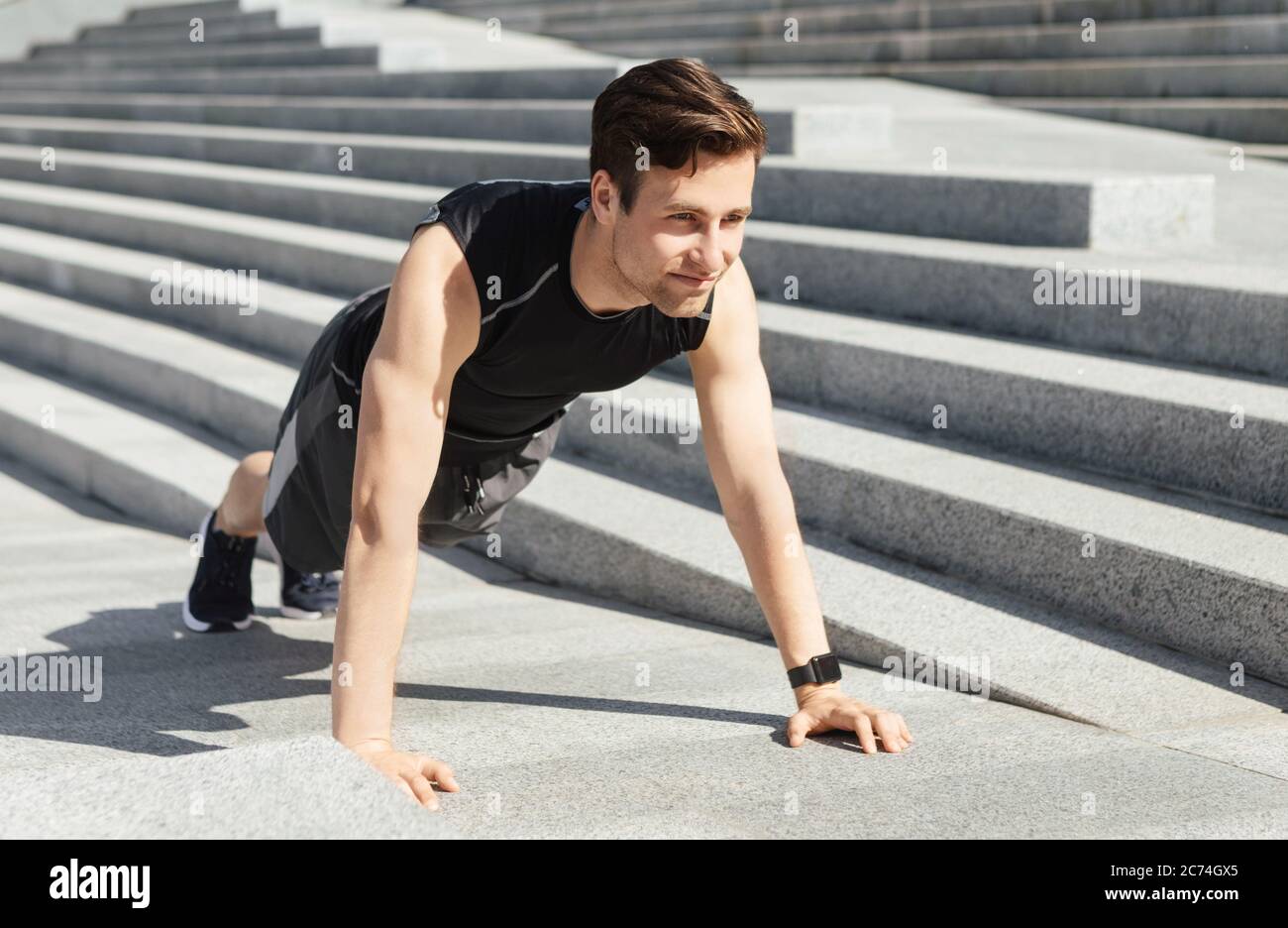 Strength training on street. Young man in sportswear doing push ups Stock Photo