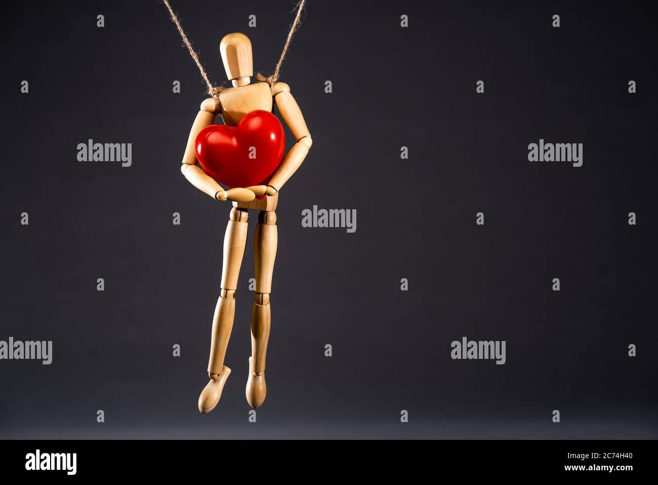 wooden on strings with red heart isolated on black Stock