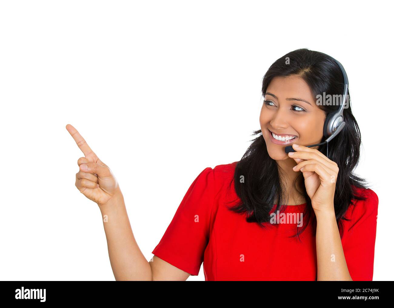 Closeup portrait of a smiling female customer representative with phone headset pointing at copy space isolated on white background. Stock Photo