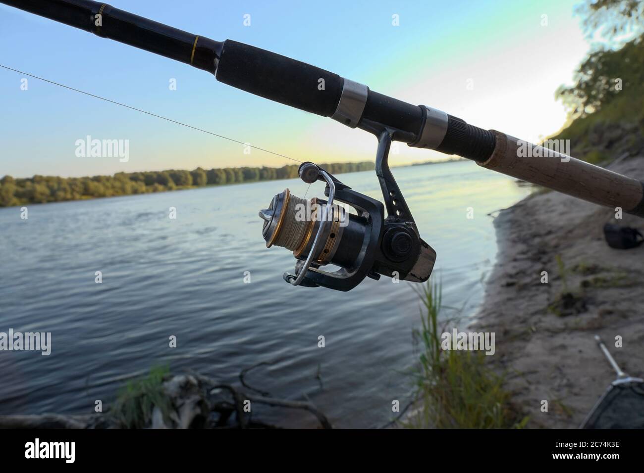 fishing rod with reel and fishing line lies on the river bank Stock Photo -  Alamy