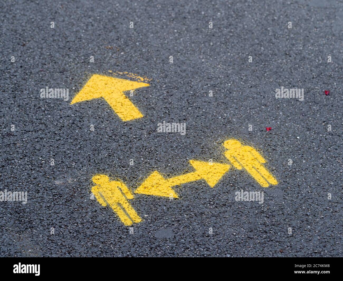 Yellow socially distanced and one way directional sign for pedestrians in street. UK Covid precaution. Stock Photo