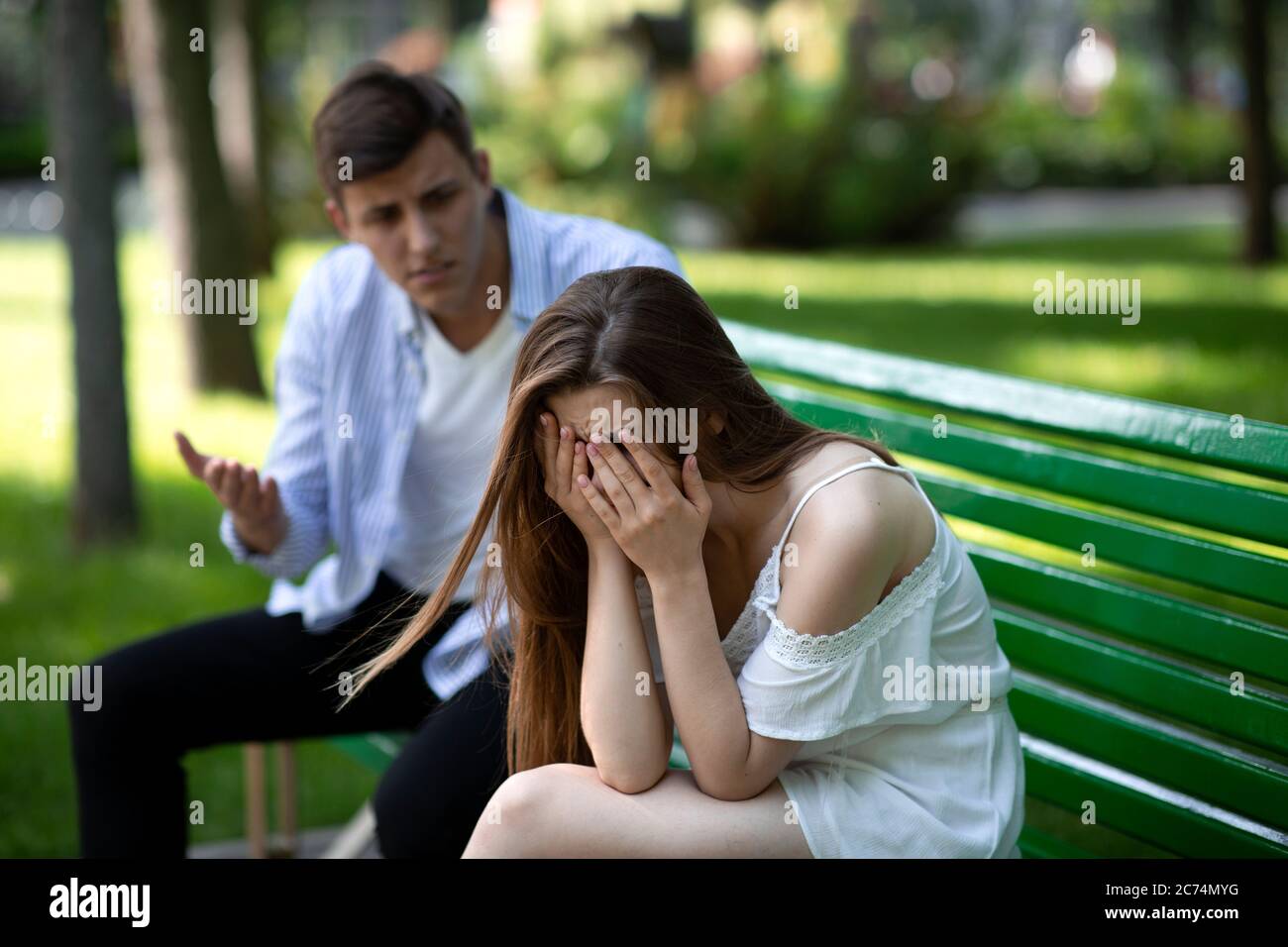 Sad young girl crying during conflict with her boyfriend on bench ...