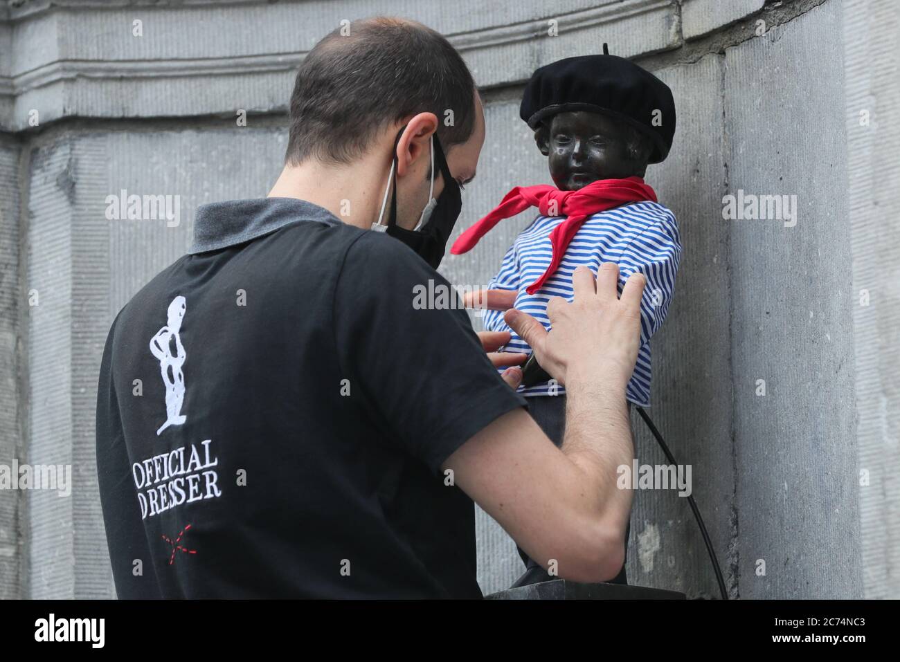 Brussels, Belgium. 14th July, 2020. An official dresser dresses the Manneken-Pis up in Brussels, Belgium, July 14, 2020. Manneken-Pis, the symbol of Brussels folklore, gets costumes at major events. He wore a suit with beret and baguette on Tuesday to commemorate the French national day which falls on July 14 every year. Credit: Zheng Huansong/Xinhua/Alamy Live News Stock Photo