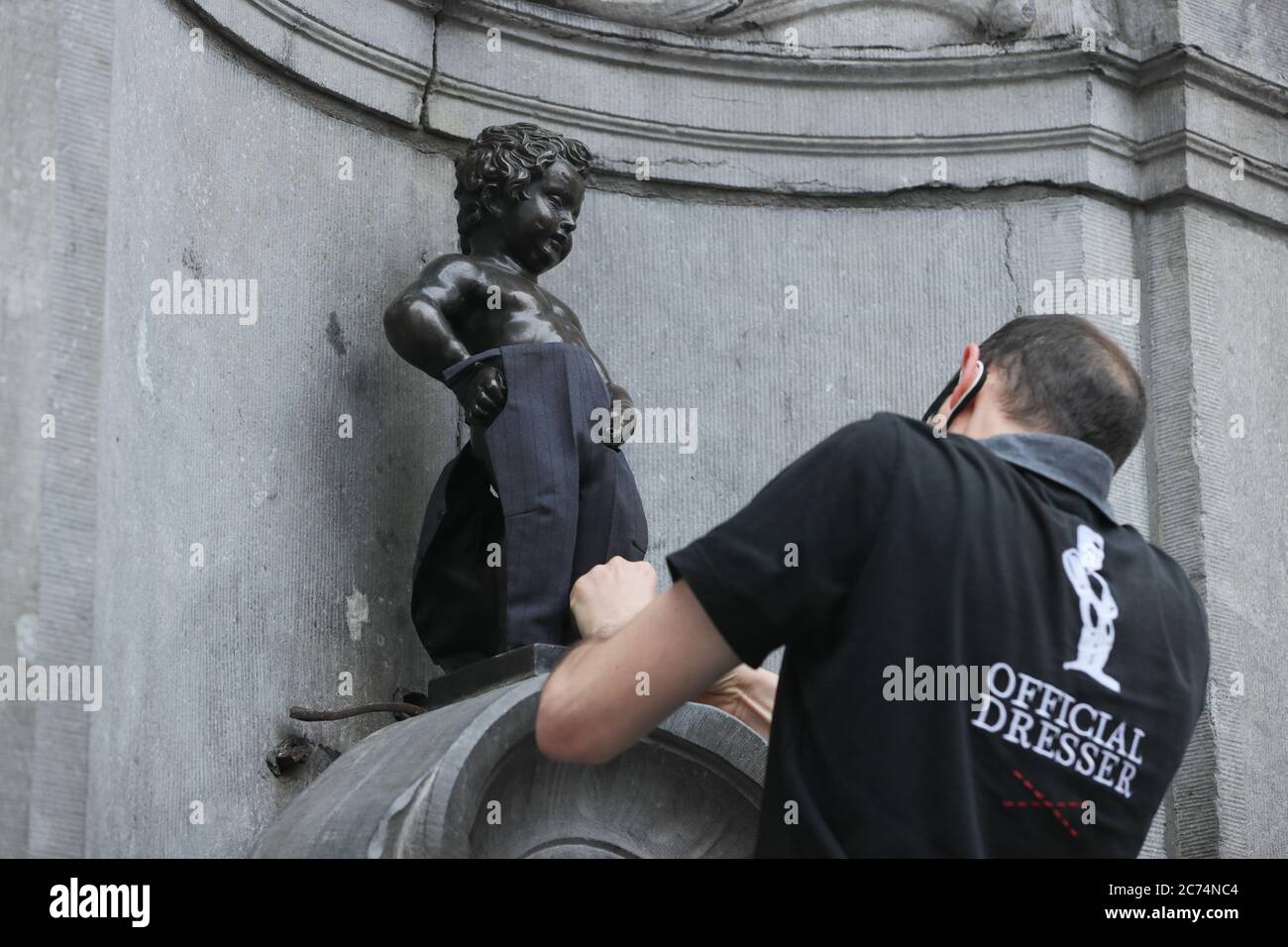 Brussels, Belgium. 14th July, 2020. An official dresser dresses the Manneken-Pis up in Brussels, Belgium, July 14, 2020. Manneken-Pis, the symbol of Brussels folklore, gets costumes at major events. He wore a suit with beret and baguette on Tuesday to commemorate the French national day which falls on July 14 every year. Credit: Zheng Huansong/Xinhua/Alamy Live News Stock Photo