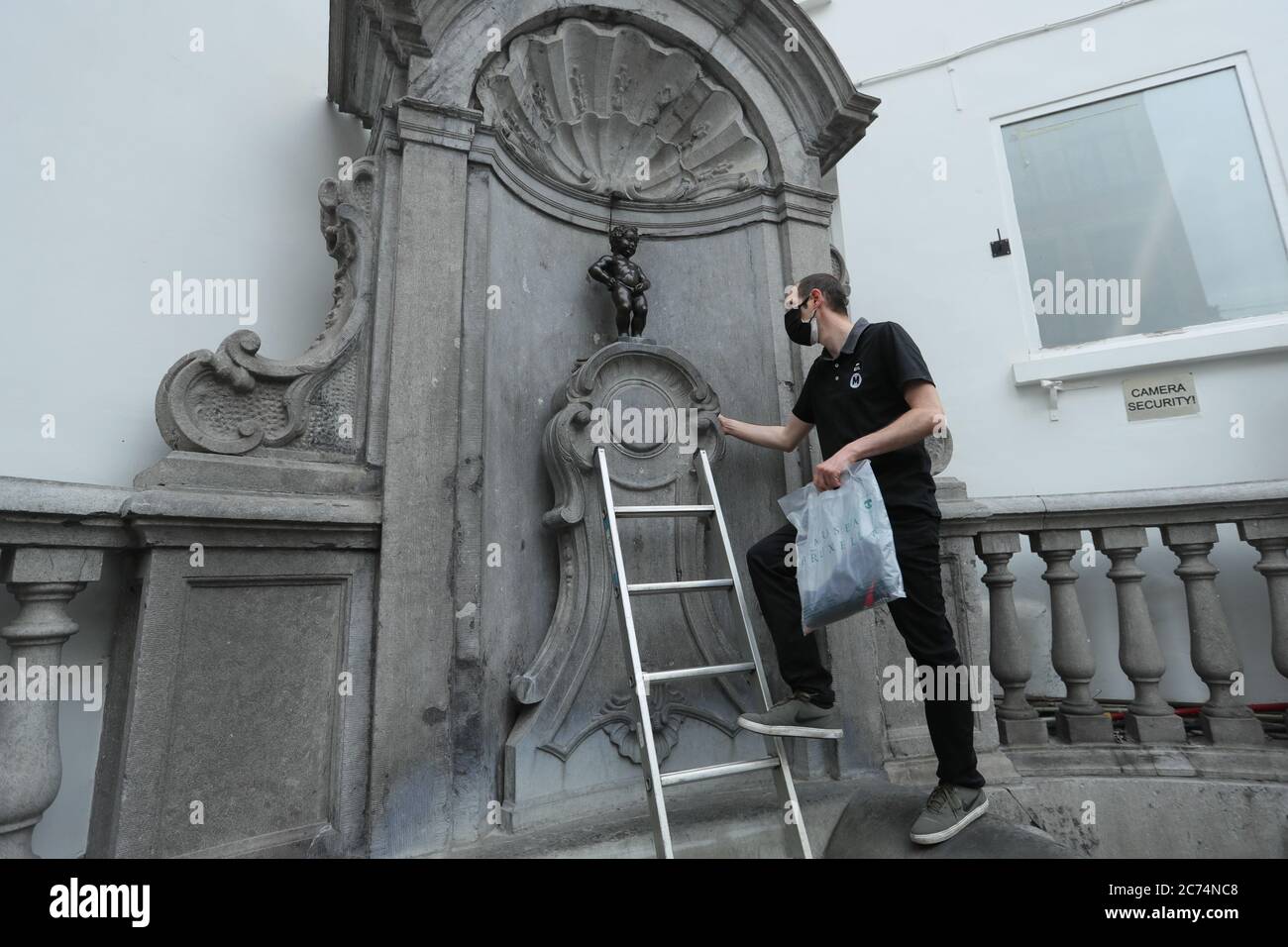 Brussels, Belgium. 14th July, 2020. An official dresser prepares to dress the Manneken-Pis up in Brussels, Belgium, July 14, 2020. Manneken-Pis, the symbol of Brussels folklore, gets costumes at major events. He wore a suit with beret and baguette on Tuesday to commemorate the French national day which falls on July 14 every year. Credit: Zheng Huansong/Xinhua/Alamy Live News Stock Photo
