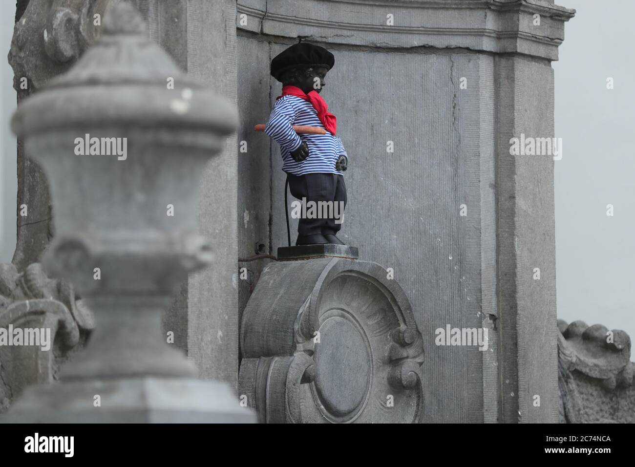 Brussels, Belgium. 14th July, 2020. The Manneken-Pis is seen in a suit with beret and baguette in Brussels, Belgium, July 14, 2020. Manneken-Pis, the symbol of Brussels folklore, gets costumes at major events. He wore a suit with beret and baguette on Tuesday to commemorate the French national day which falls on July 14 every year. Credit: Zheng Huansong/Xinhua/Alamy Live News Stock Photo
