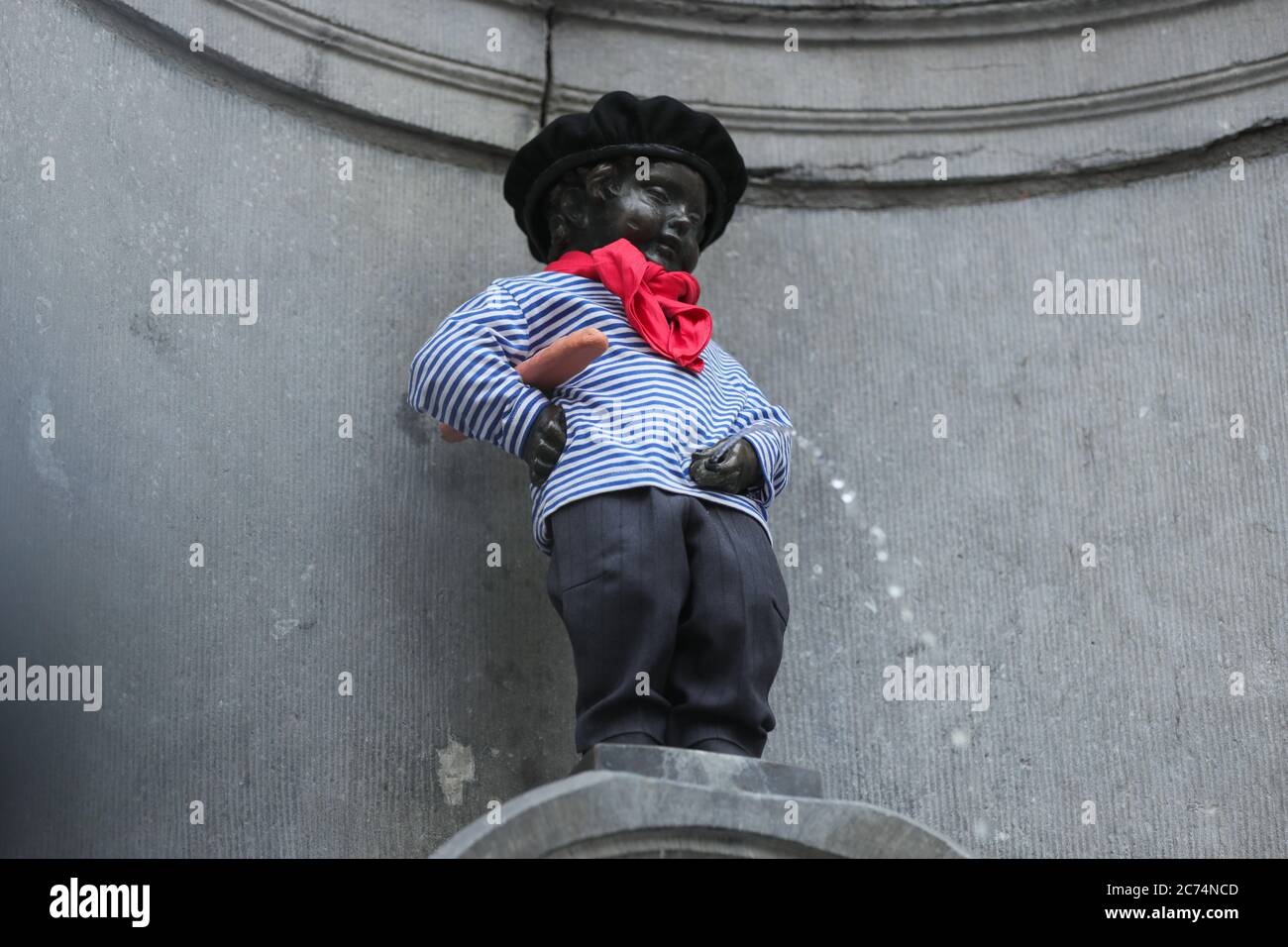 Brussels, Belgium. 14th July, 2020. The Manneken-Pis is seen in a suit with beret and baguette in Brussels, Belgium, July 14, 2020. Manneken-Pis, the symbol of Brussels folklore, gets costumes at major events. He wore a suit with beret and baguette on Tuesday to commemorate the French national day which falls on July 14 every year. Credit: Zheng Huansong/Xinhua/Alamy Live News Stock Photo
