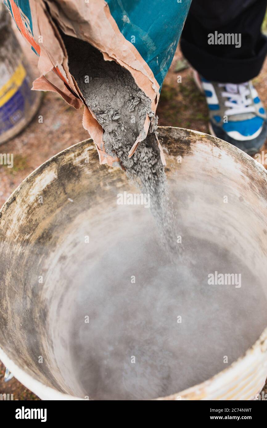 A professional craftsman kneads mortar in a bucket with a mixer