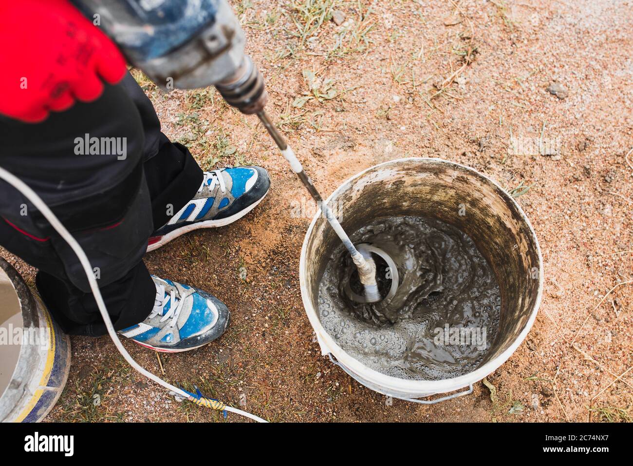 A professional craftsman kneads mortar in a bucket with a mixer