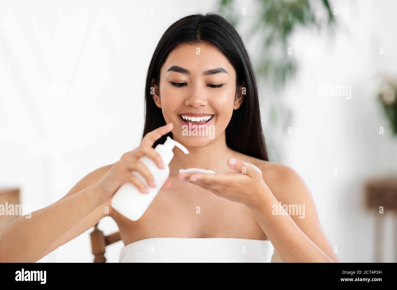 Pretty asian girl applying cleansing lotion on cotton pad Stock Photo