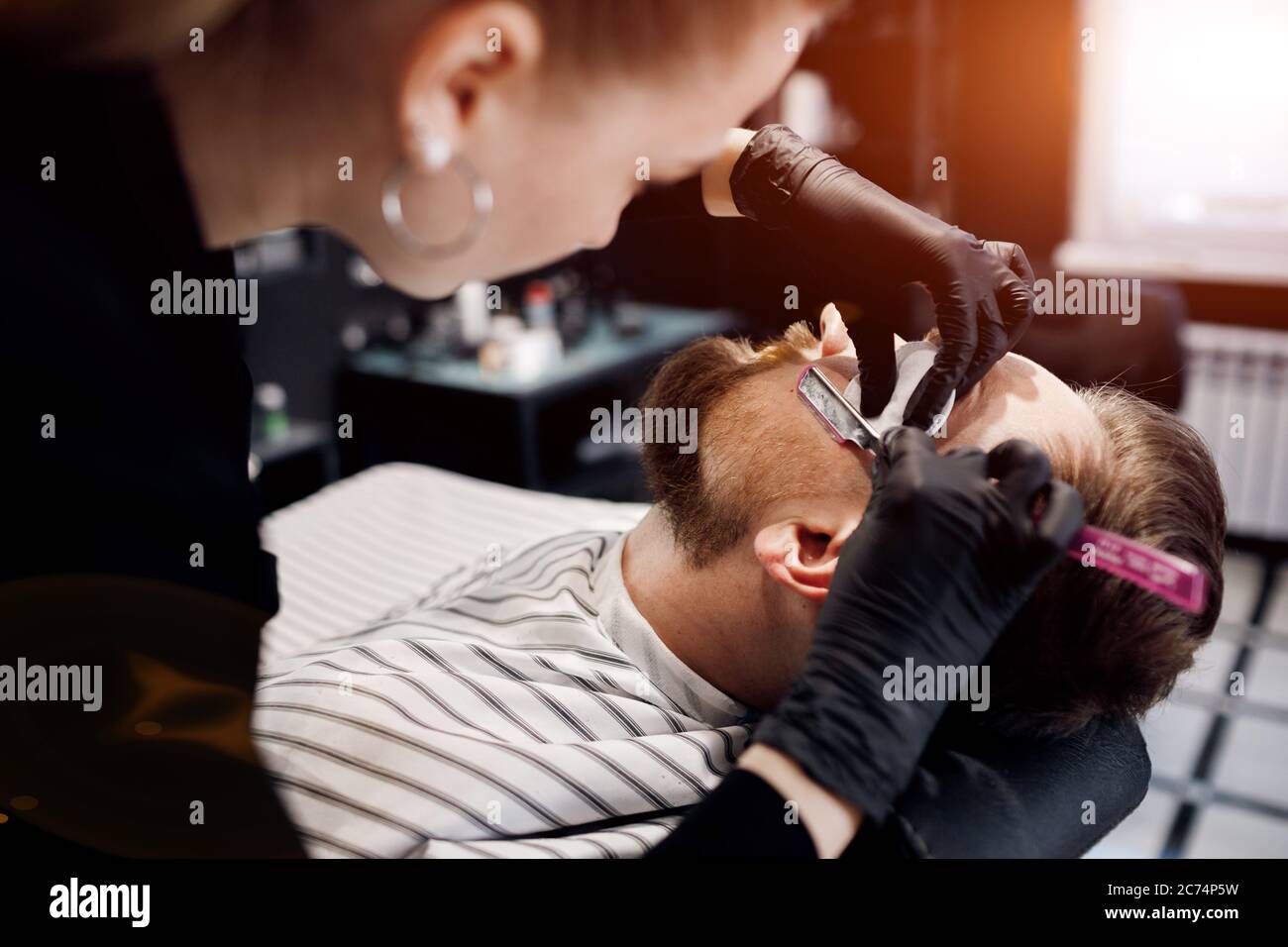 Barber shaving a man in barbershop, close up Stock Photo