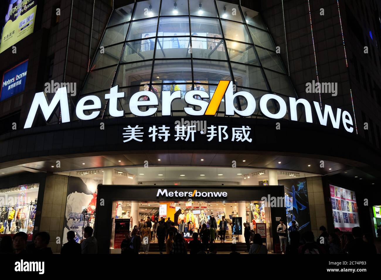 facade of Metersbonwe flagship store on Nanjing Road. Bright white shop sign. Illuminated clothing store inside. A Chinese clothing brand Stock Photo