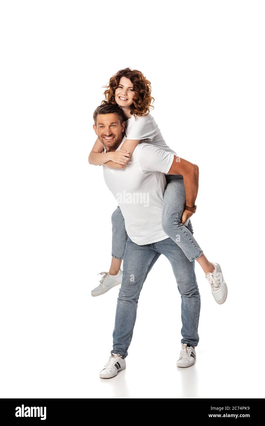 cheerful man piggybacking curly and happy wife on white Stock Photo