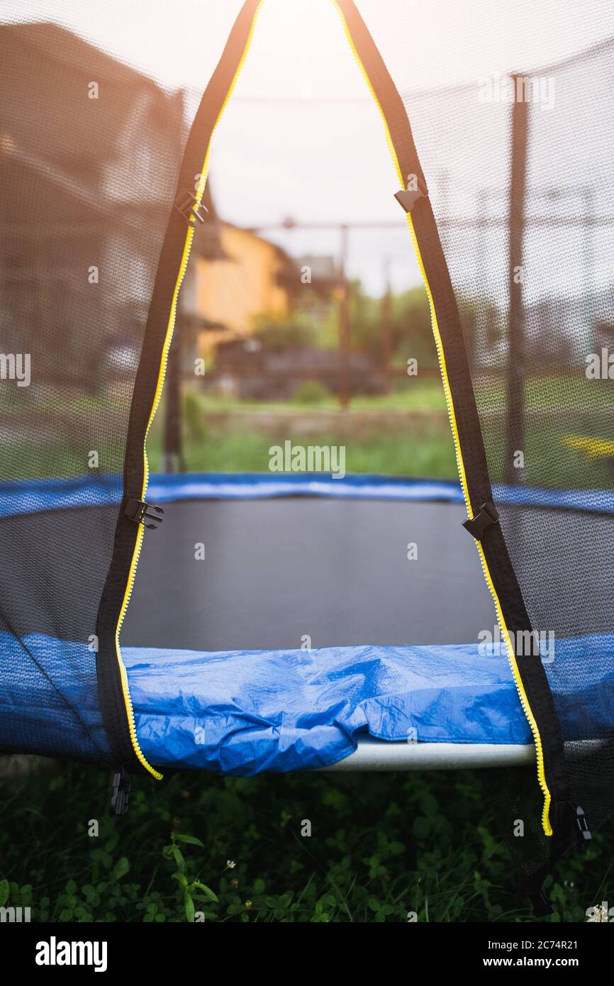 Trampoline in the backyard - entrance through an open net - outdoor activities and entertainment for the whole family Stock Photo
