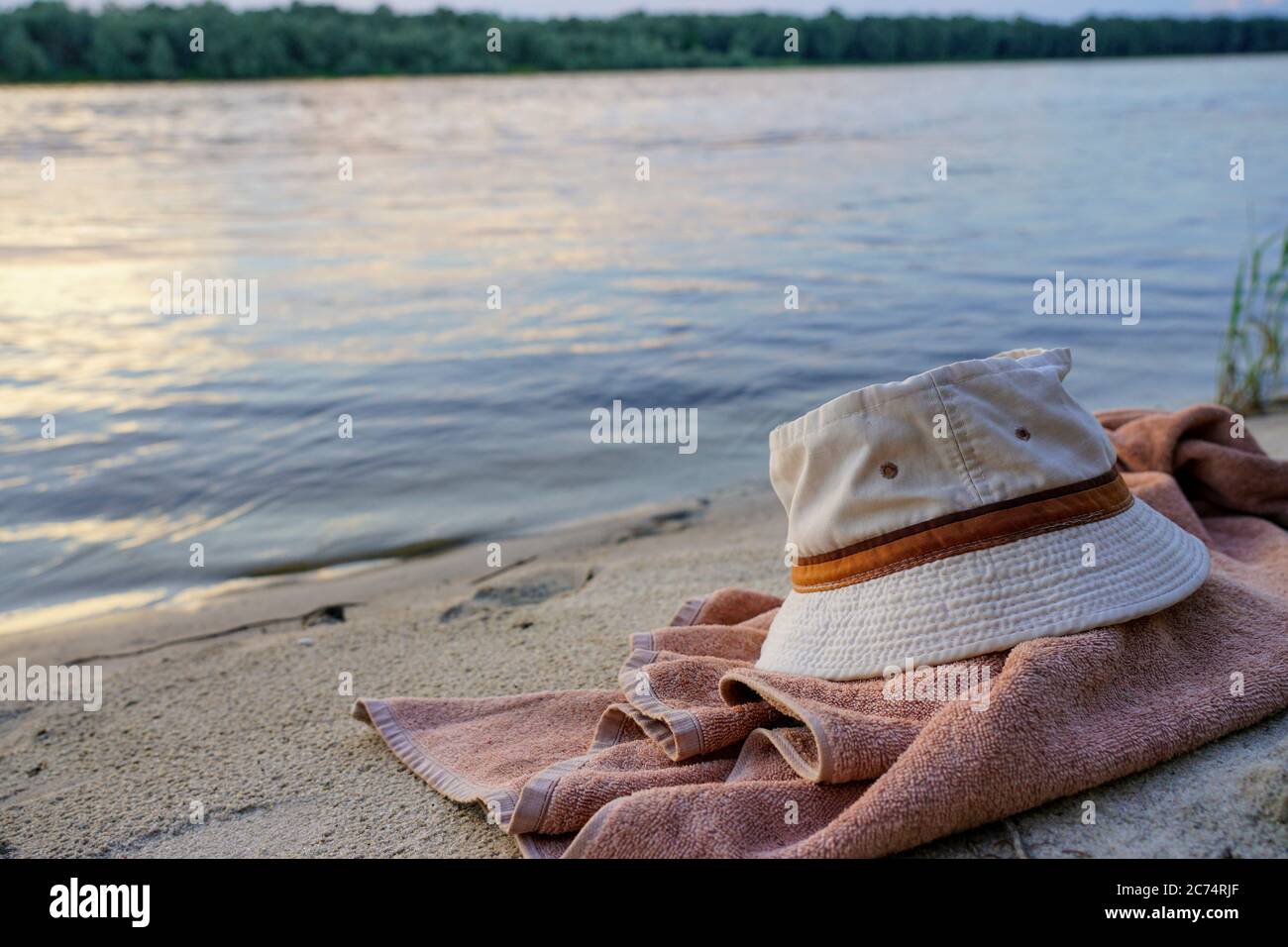 towel and hat lie on the sandy shore in the evening Stock Photo - Alamy