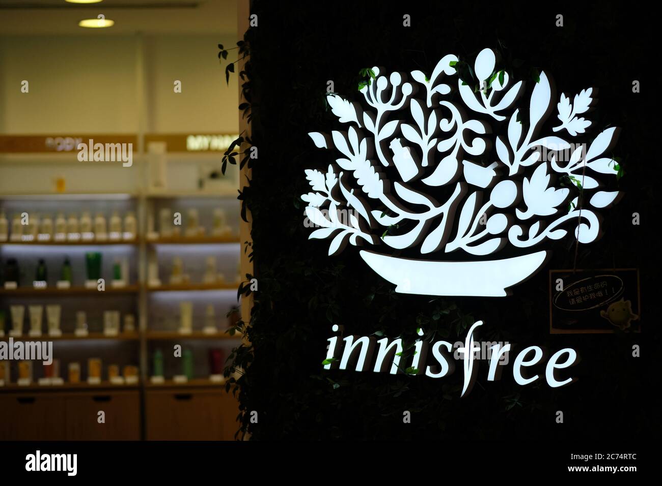 close up innisfree's logo on exterior wall of store at night. A South Korean naturalism-oriented cosmetics brand. Blur background. Stock Photo