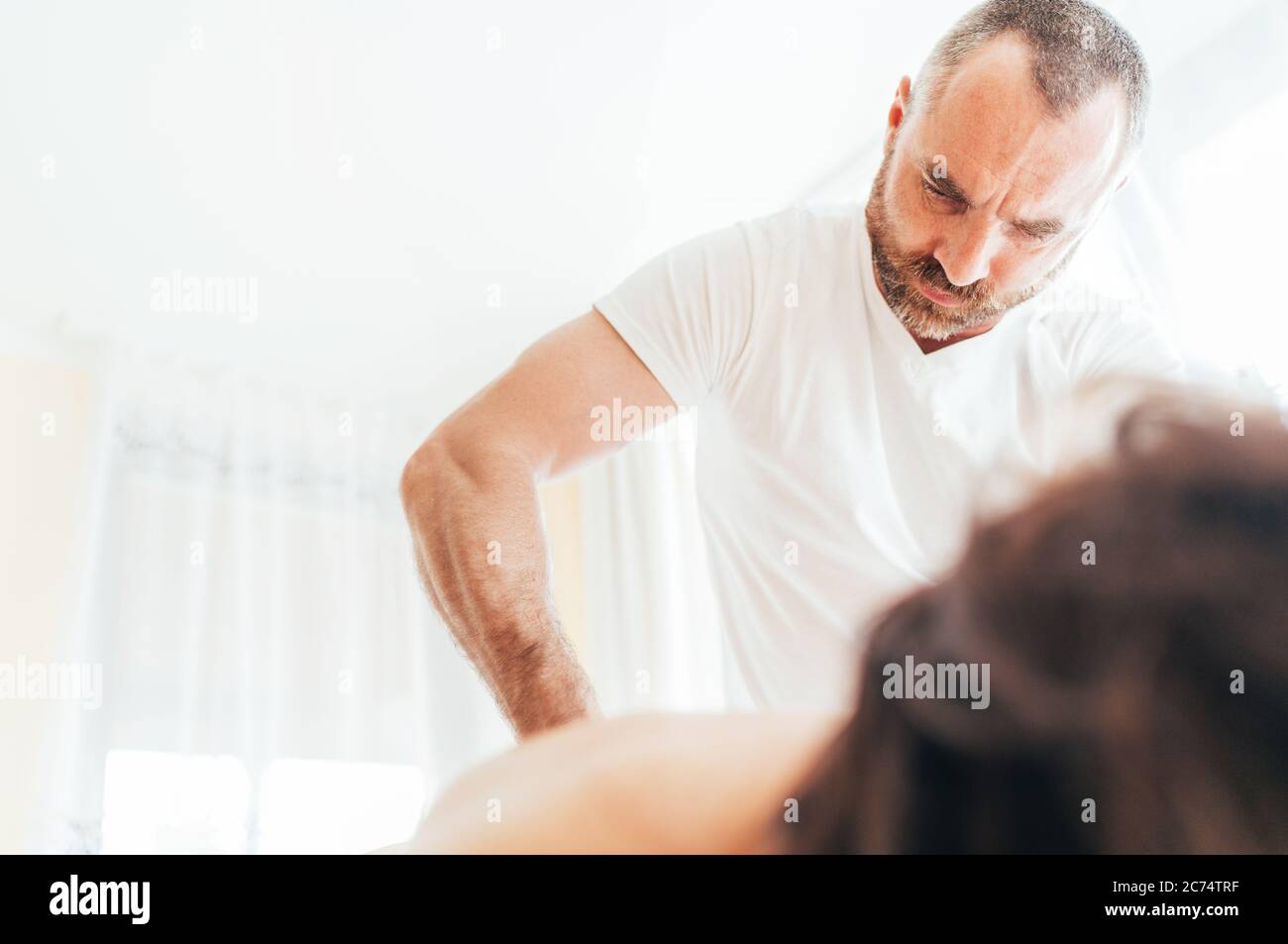 Bearded Masseur man doing massage manipulations on the low back area