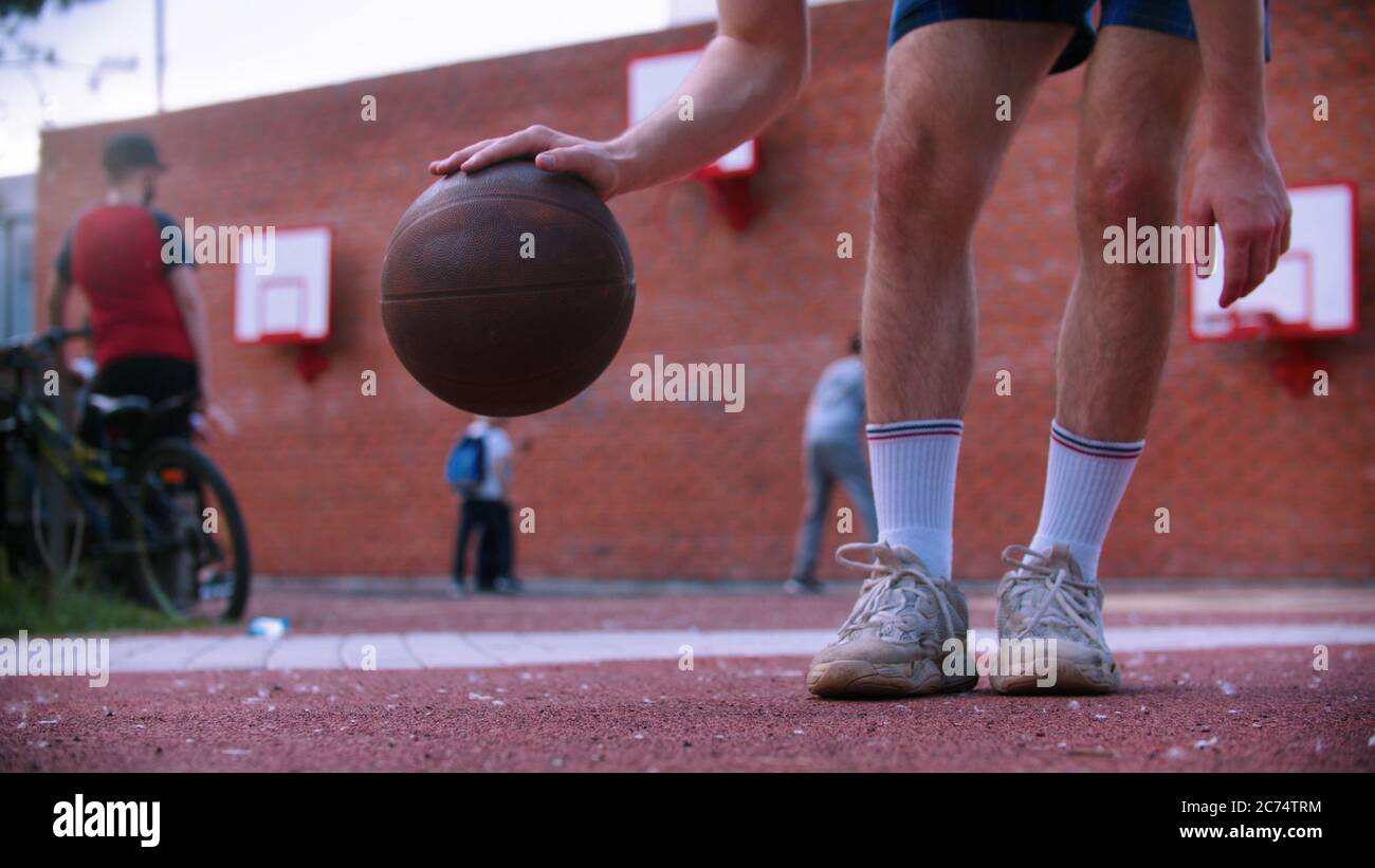 Young man on basketball playground hitting the ball. Mid shot Stock Photo