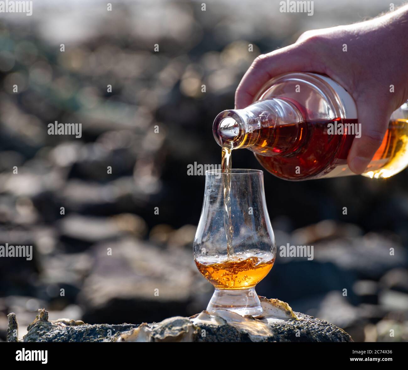 Pouring of Scotch whisky in tasting glass in sunny day Stock Photo