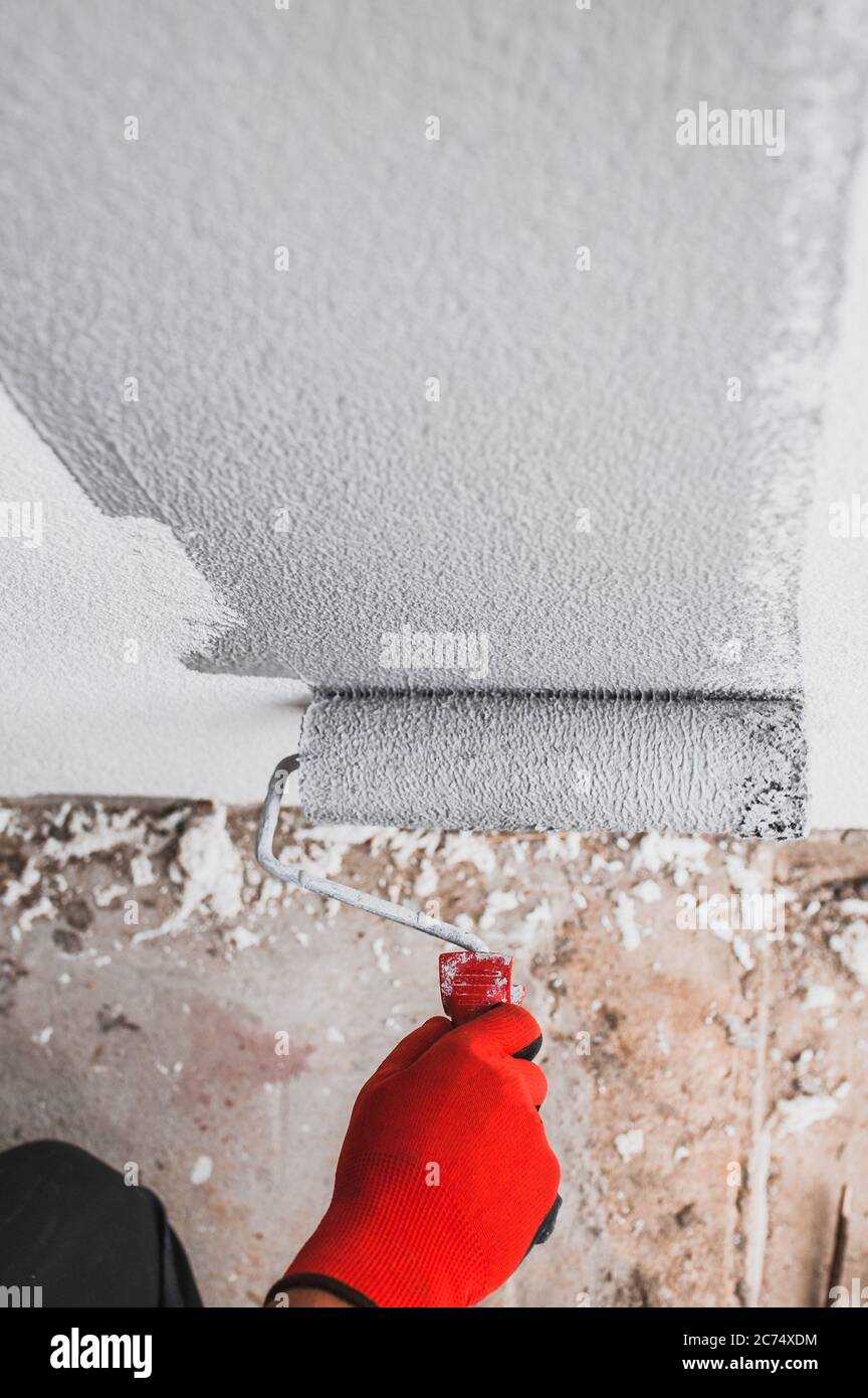 Fur roller with paint in the hand of the painter during work painting the wall using
