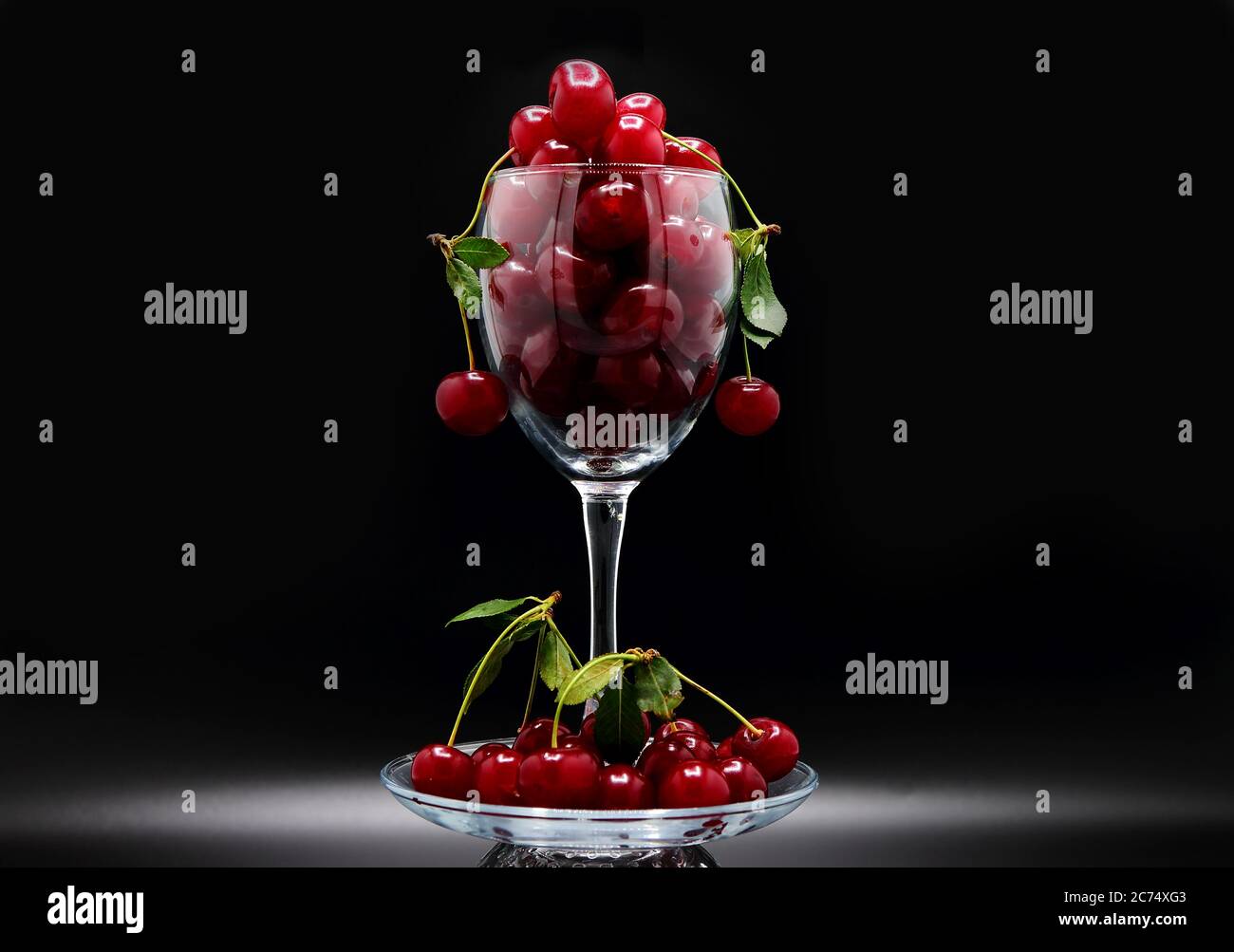 Full wine glass of ripe cherries on a black background. Natural product. Natural color. Close-up. Stock Photo