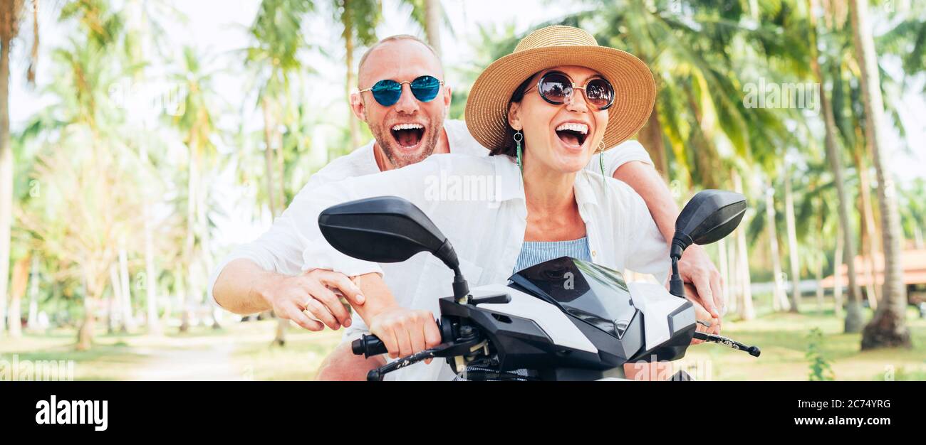 Happy smiling and screaming male tourist in helmet and sunglasses riding motorbike  scooter during his tropical vacation under palm trees Stock Photo - Alamy