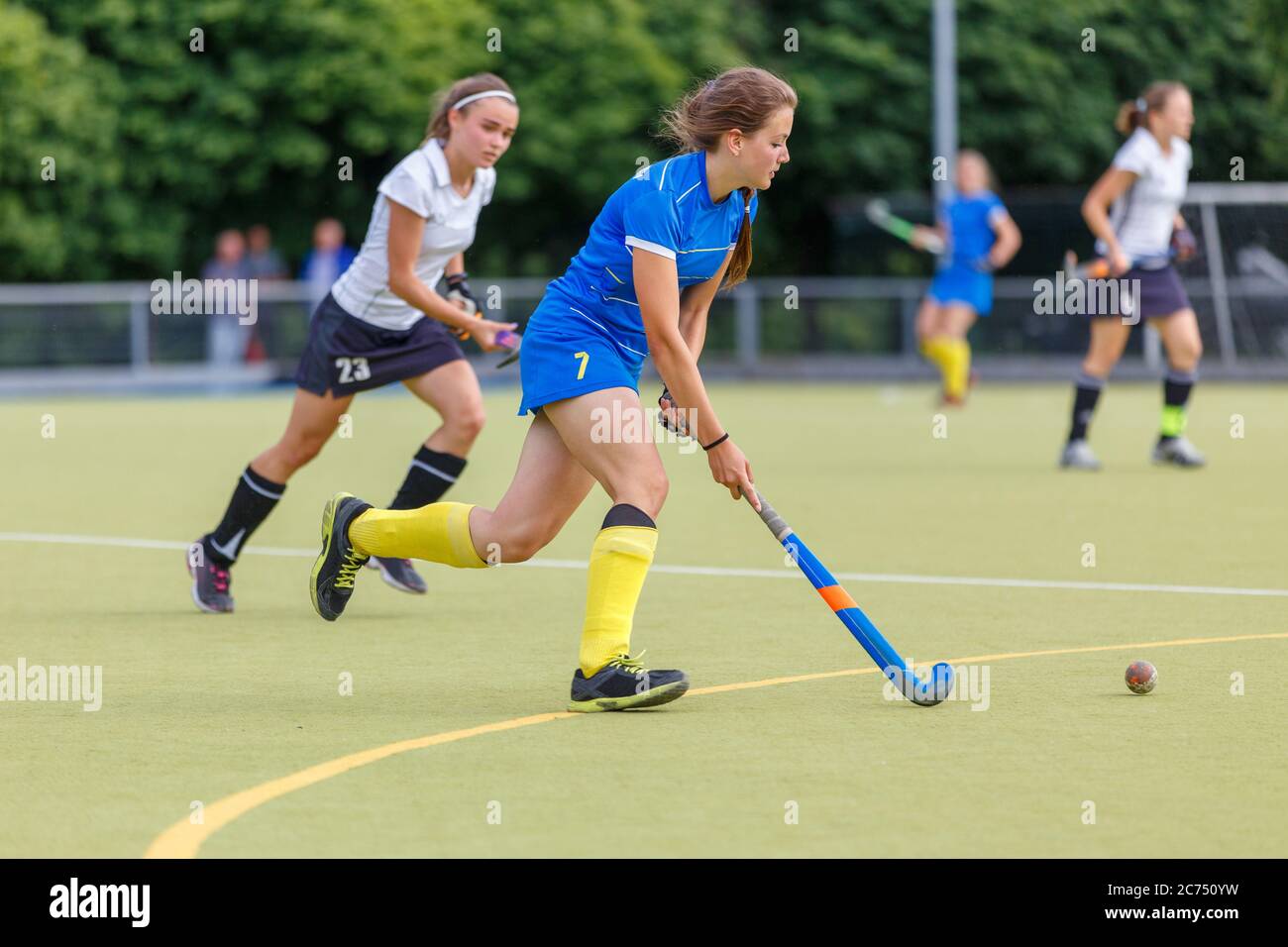 Young women playing field hockey game on the pitch. Female field hockey