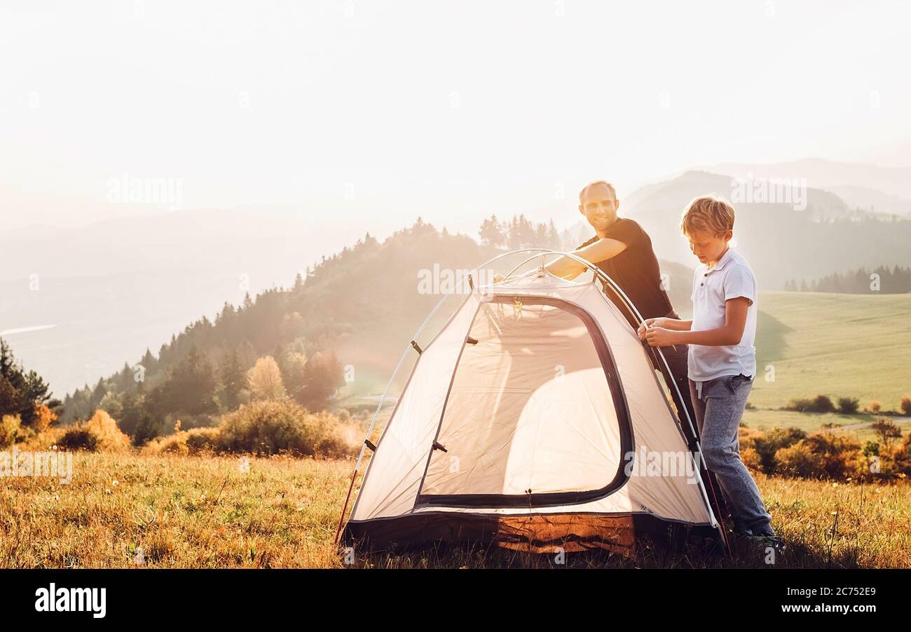 Father and son installing tent on forest glade.Trekking with kids concept image Stock Photo