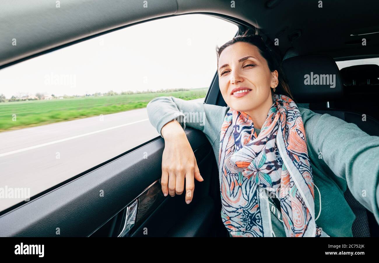 Woman in car portrait with wavy hair looks out car window wide angle