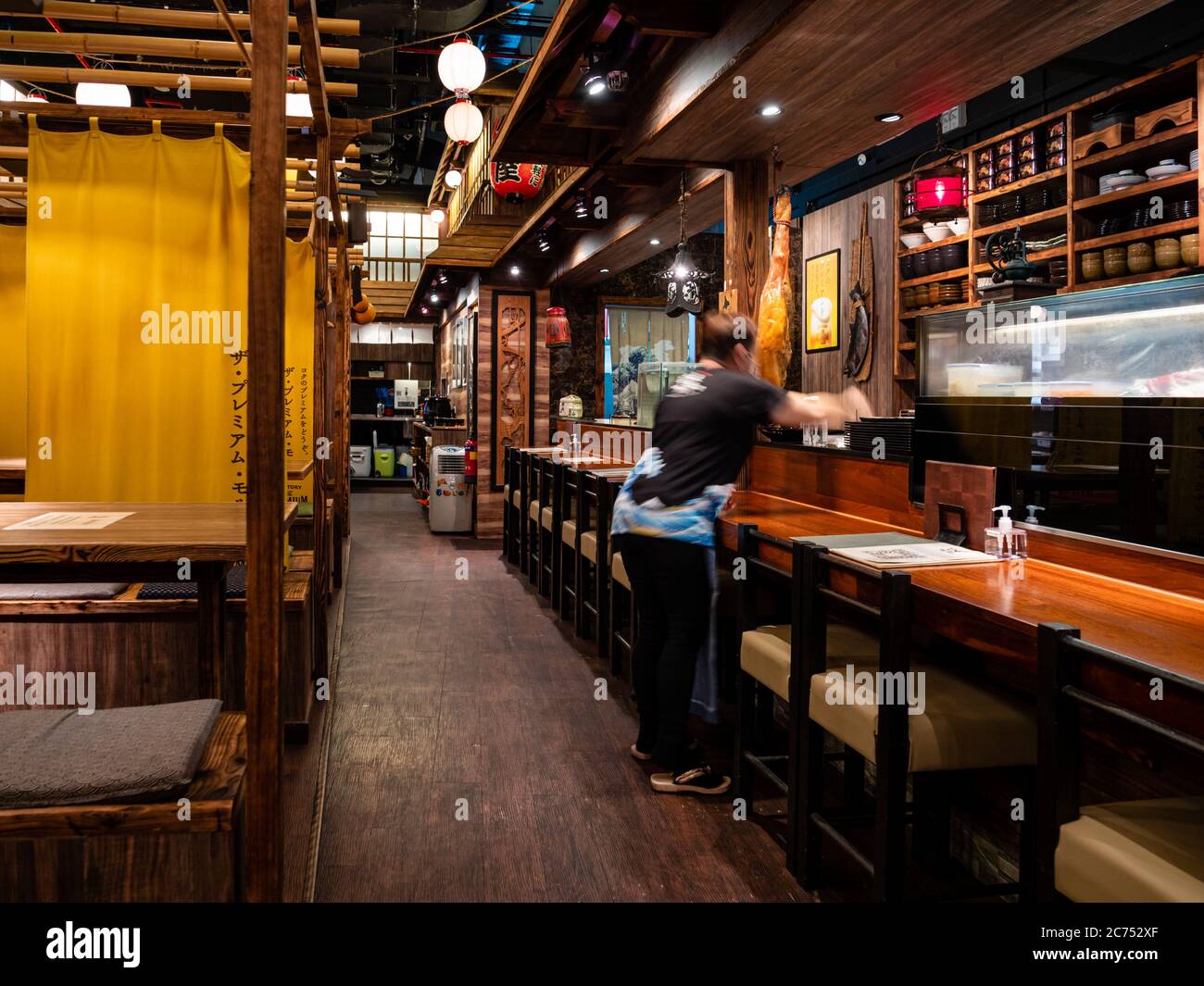SINGAPORE – JULY 08 – A waitress cleans the empty tables at The Public Izakaya Japanese restaurant in Tanjong Pagar, Singapore in the evening. Busines Stock Photo