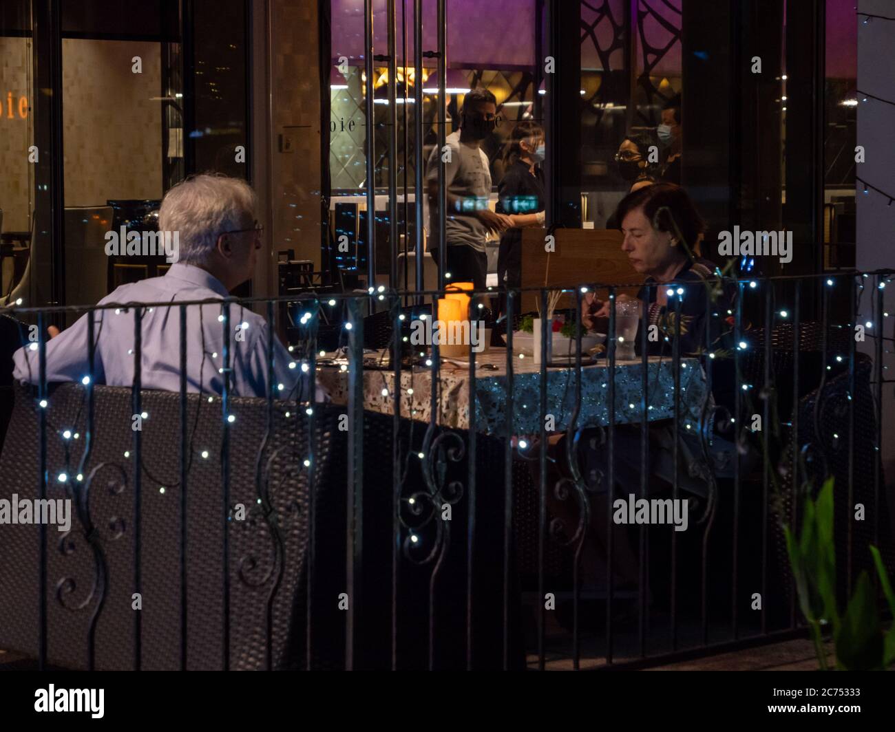 SINGAPORE – JULY 08 – Elderly White Caucasian couple dining al-fresco at Joie vegetarian restaurant, Orchard Central, Orchard Road Singapore in the ev Stock Photo