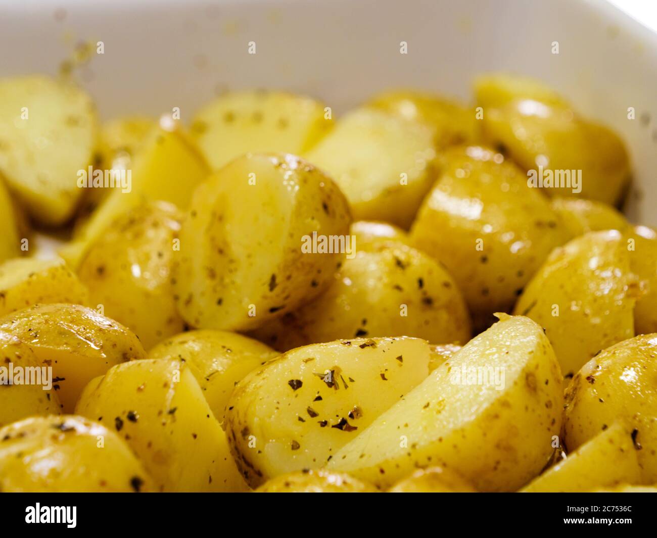 Macro close-up of sliced potatoes seasoned with herbs and olive oil prior to being put in the oven Stock Photo