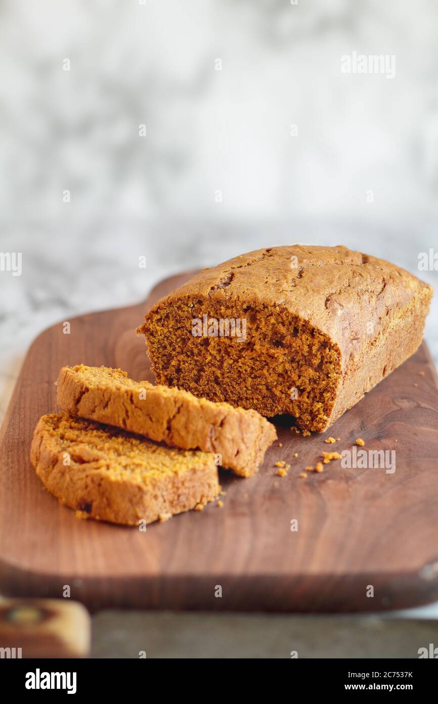 Fresh baked homemade pumpkin bread cut into slices on a cutting board with old knife. Selective focus with blurred foreground and background. Stock Photo