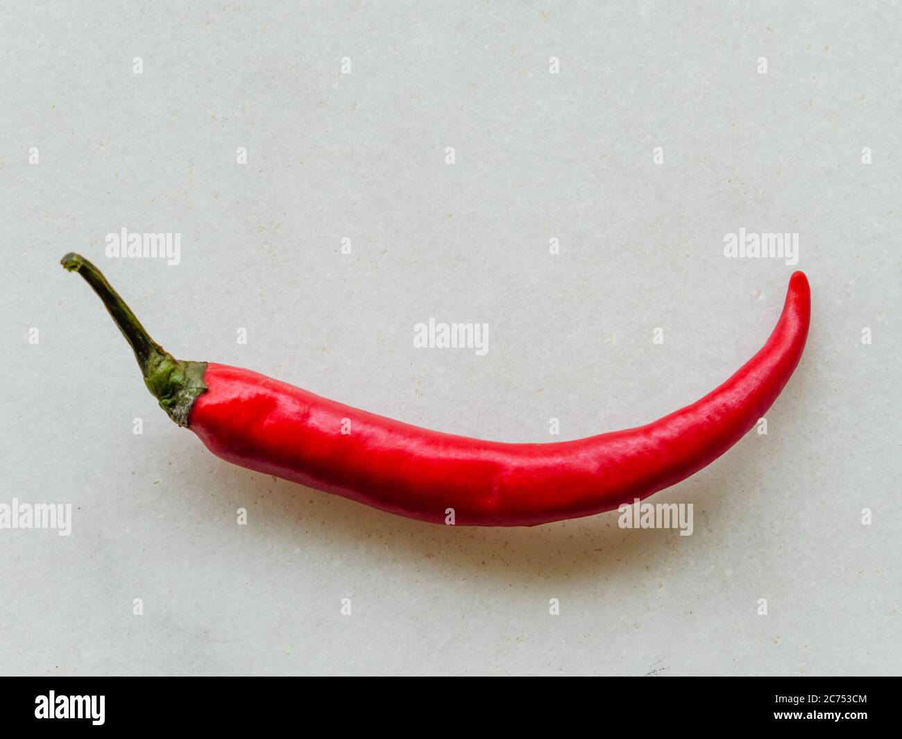 Close-up of a bright-red chilli pepper isolated on off-white background Stock Photo