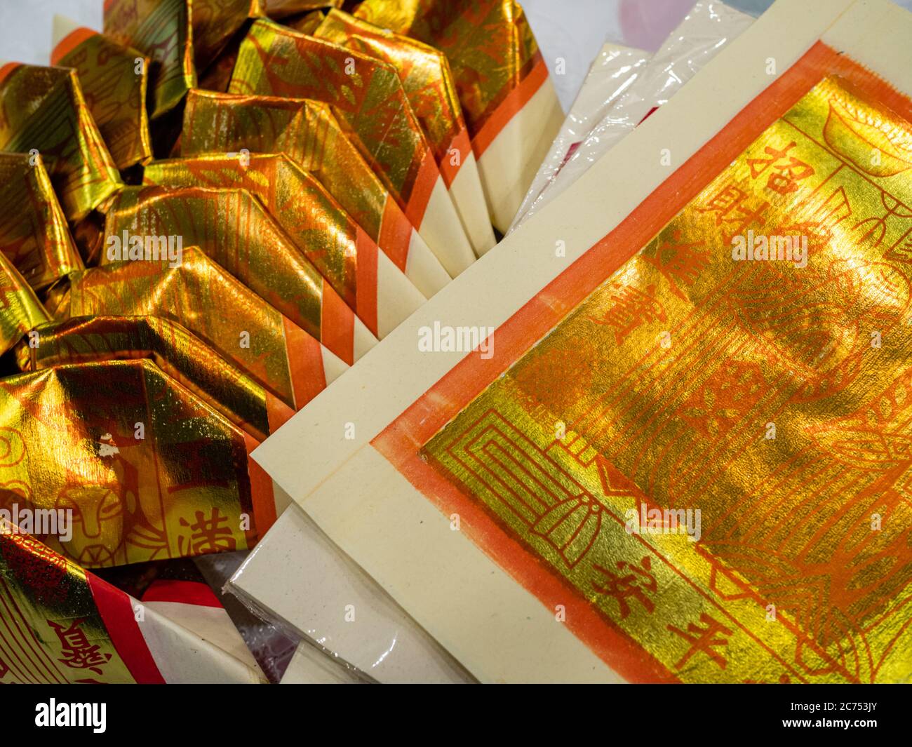 Gold Chinese joss paper aka ghost money, spirit money or hell bank notes folded into the shape of a Chinese gold ingot for ancestral worship or prayer Stock Photo