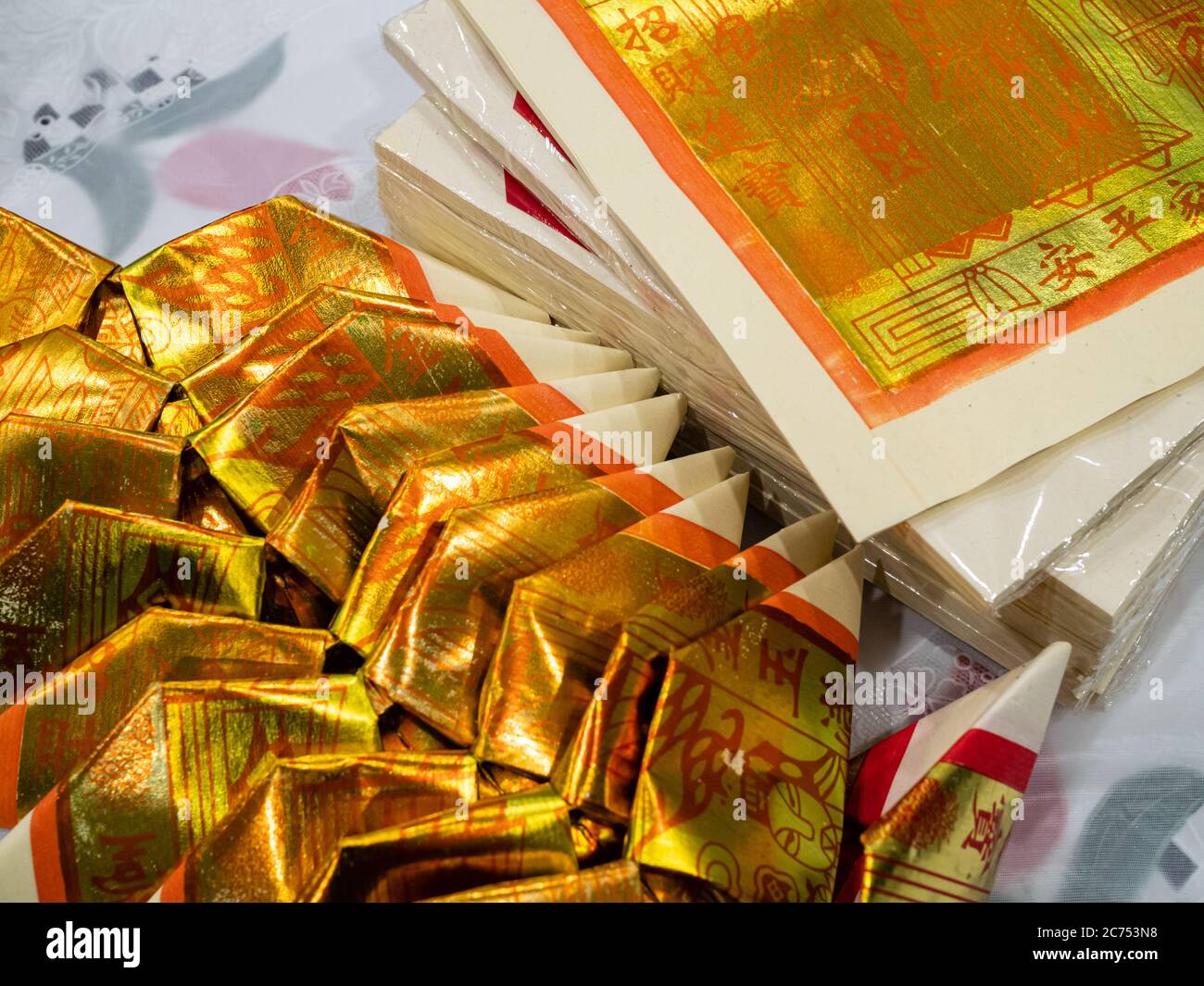 Gold Chinese joss paper aka ghost money, spirit money or hell bank notes folded into the shape of a Chinese gold ingot for ancestral worship or prayer Stock Photo