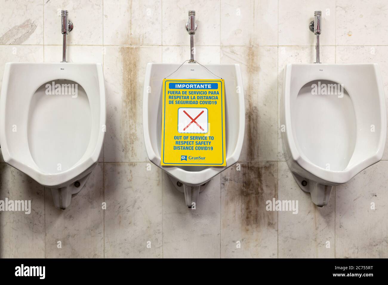 Row of urinals with one marked out of use to maintain distancing in the aftermath of the covid