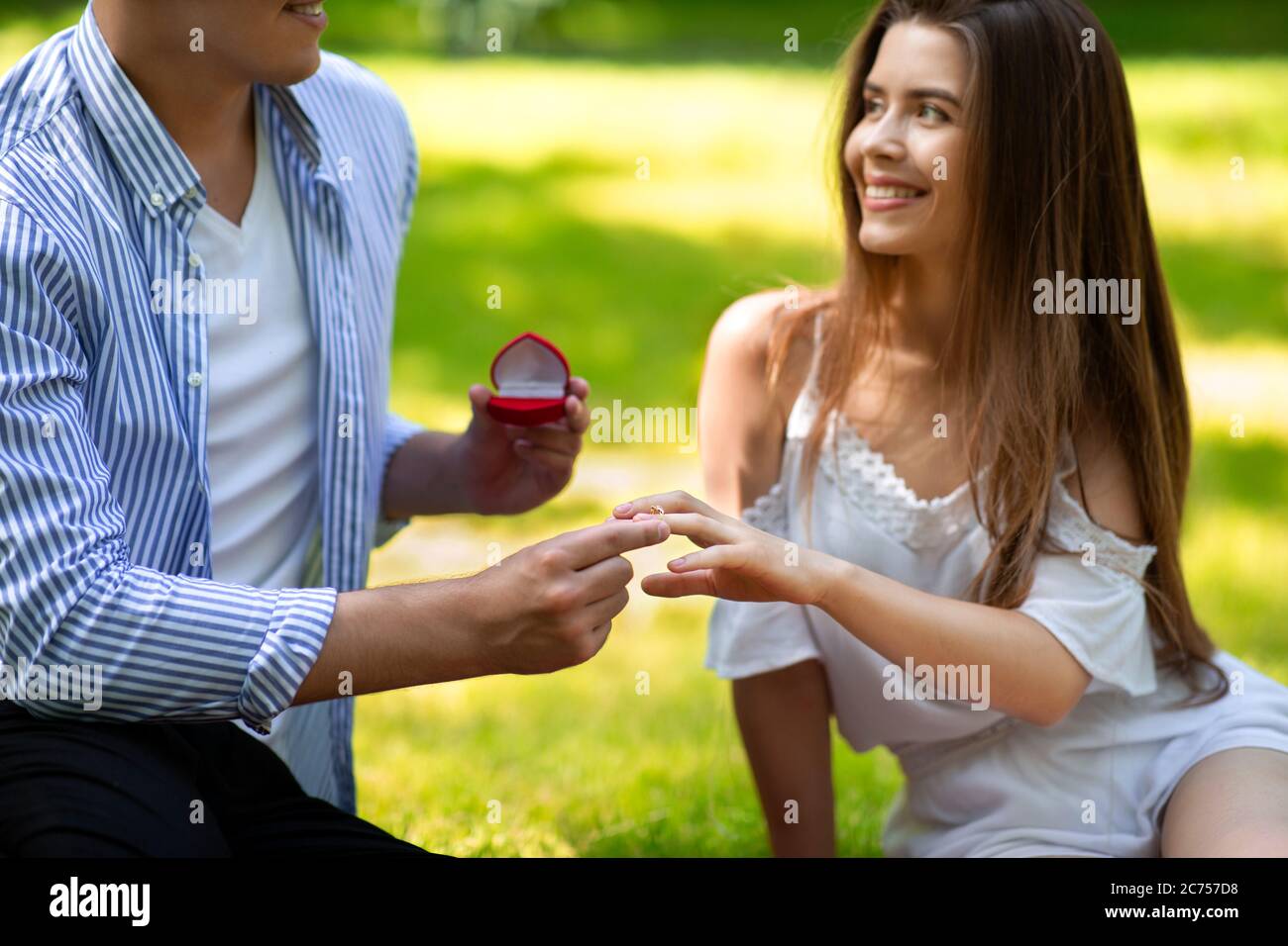 Summer proposal. Affectionate guy putting engagement ring on woman's