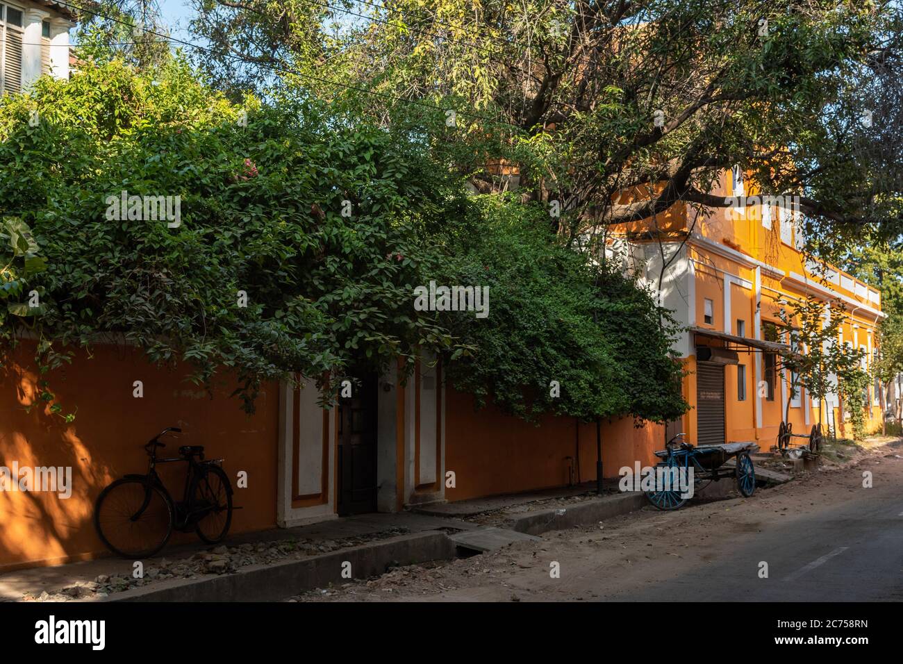 Pondicherry. India - February 2020: A street in the French Quarter of the White Town lined with old French era yellow orange houses  and lush foliage. Stock Photo