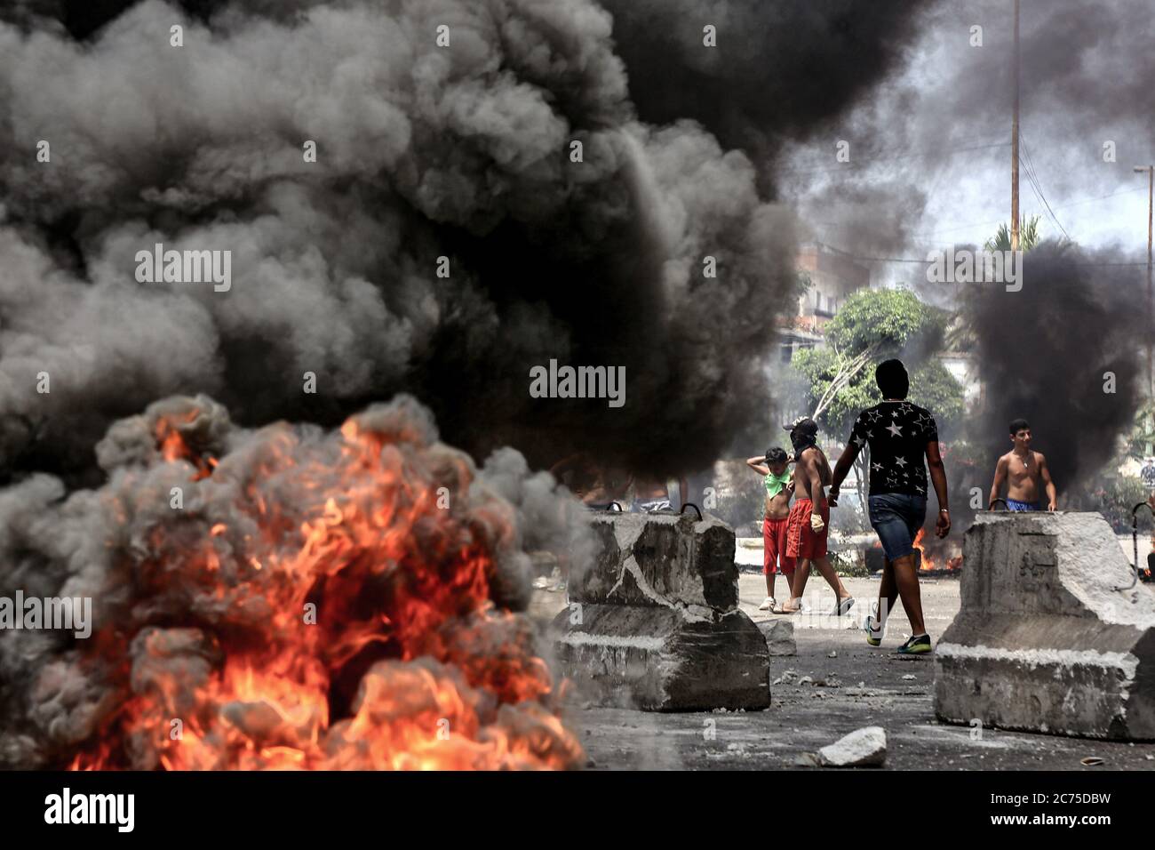 Beirut, Lebanon. 14th July, 2020. Demonstrators block the main road in Ouzai, south of Beirut by burning tyres during an anti-government protest. Credit: Marwan Naamani/dpa/Alamy Live News Stock Photo