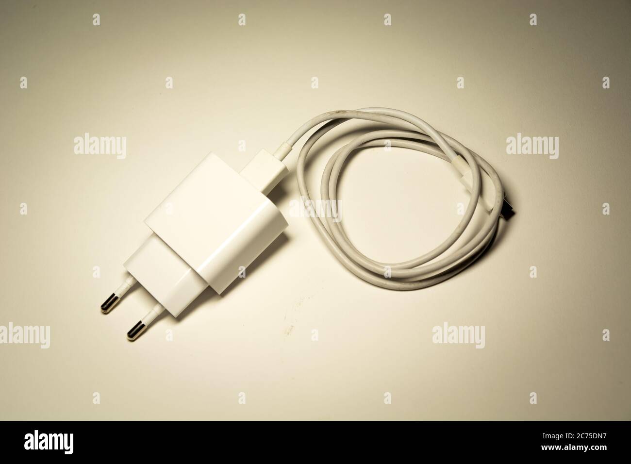 White phone charger with rolled-up cable, top view Stock Photo - Alamy