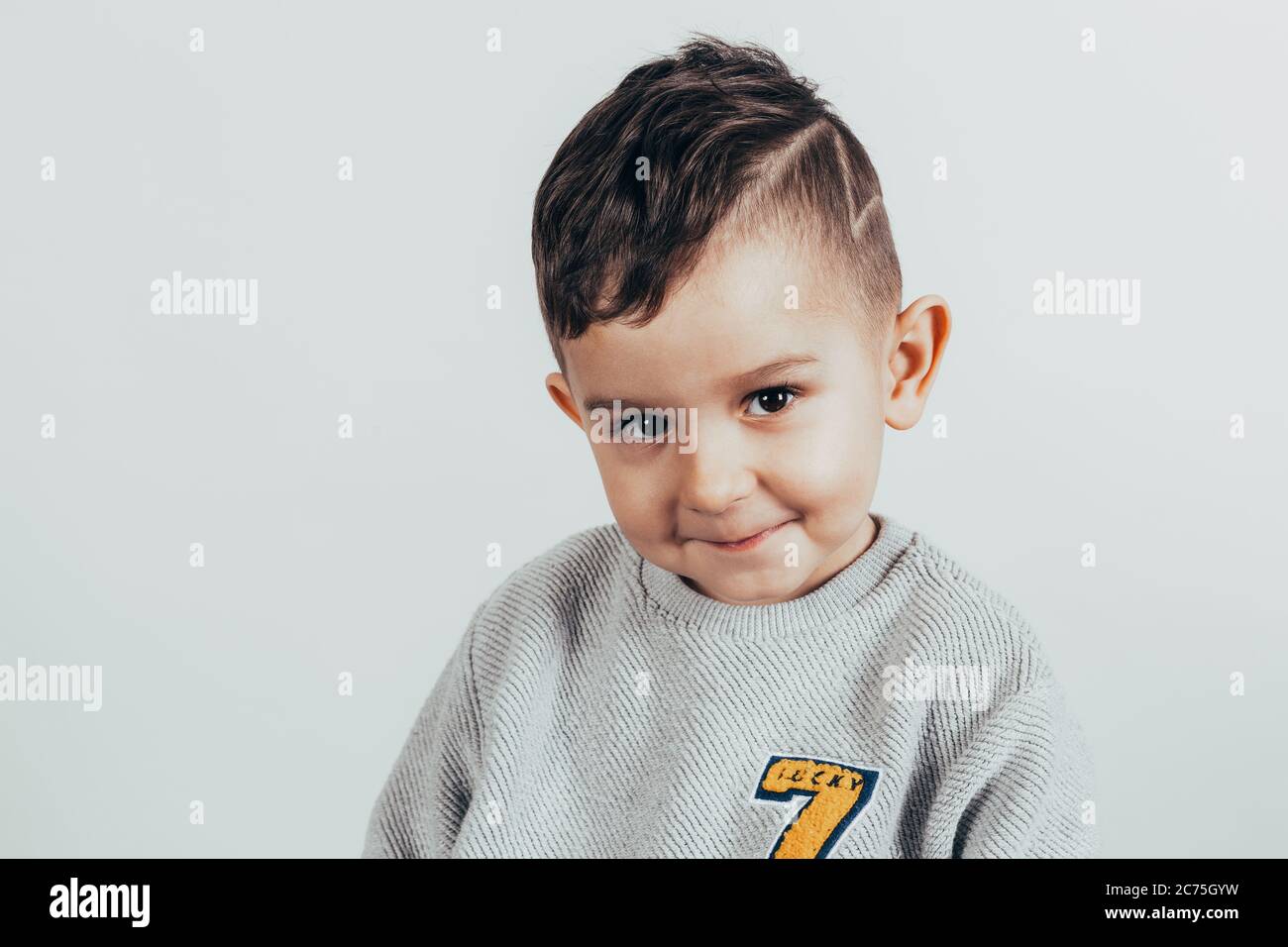 Photo of adorable young boy wearing shirt looking at camera over gray ...