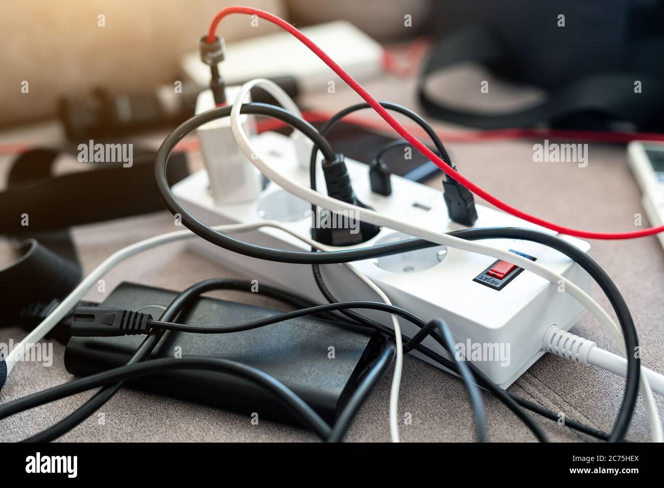 Overloaded power socket plug extendion at home. Tangled cords of home appliances and chargins gadgets mess Stock Photo