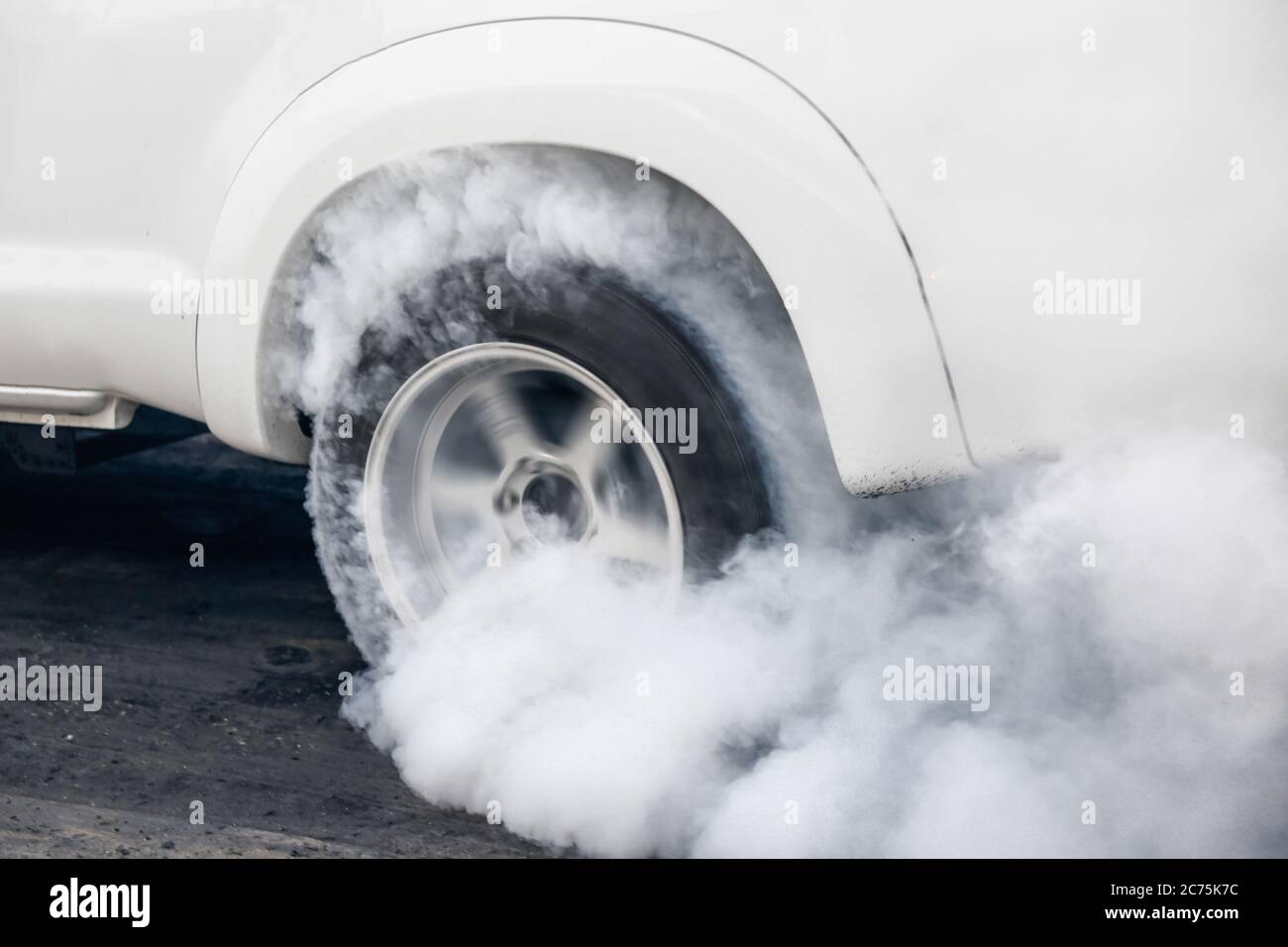 Drag racing car burns rubber off its tires in preparation for the race ...