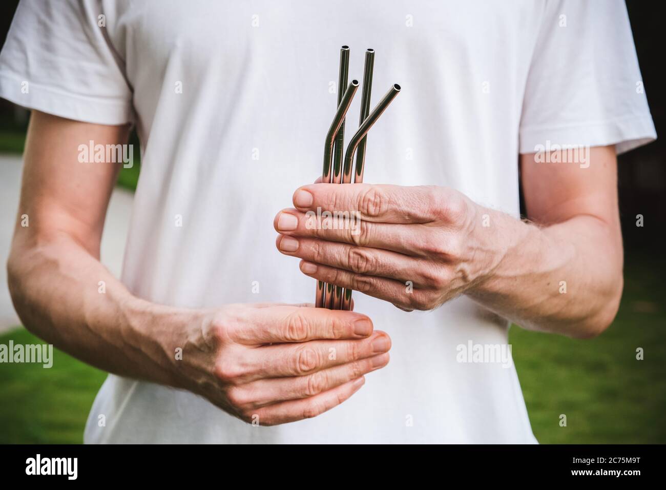 Man in white t-shirt holding a reusable steel drinking straw. Eco lifestyle and zero waste concept. Plastic free Stock Photo