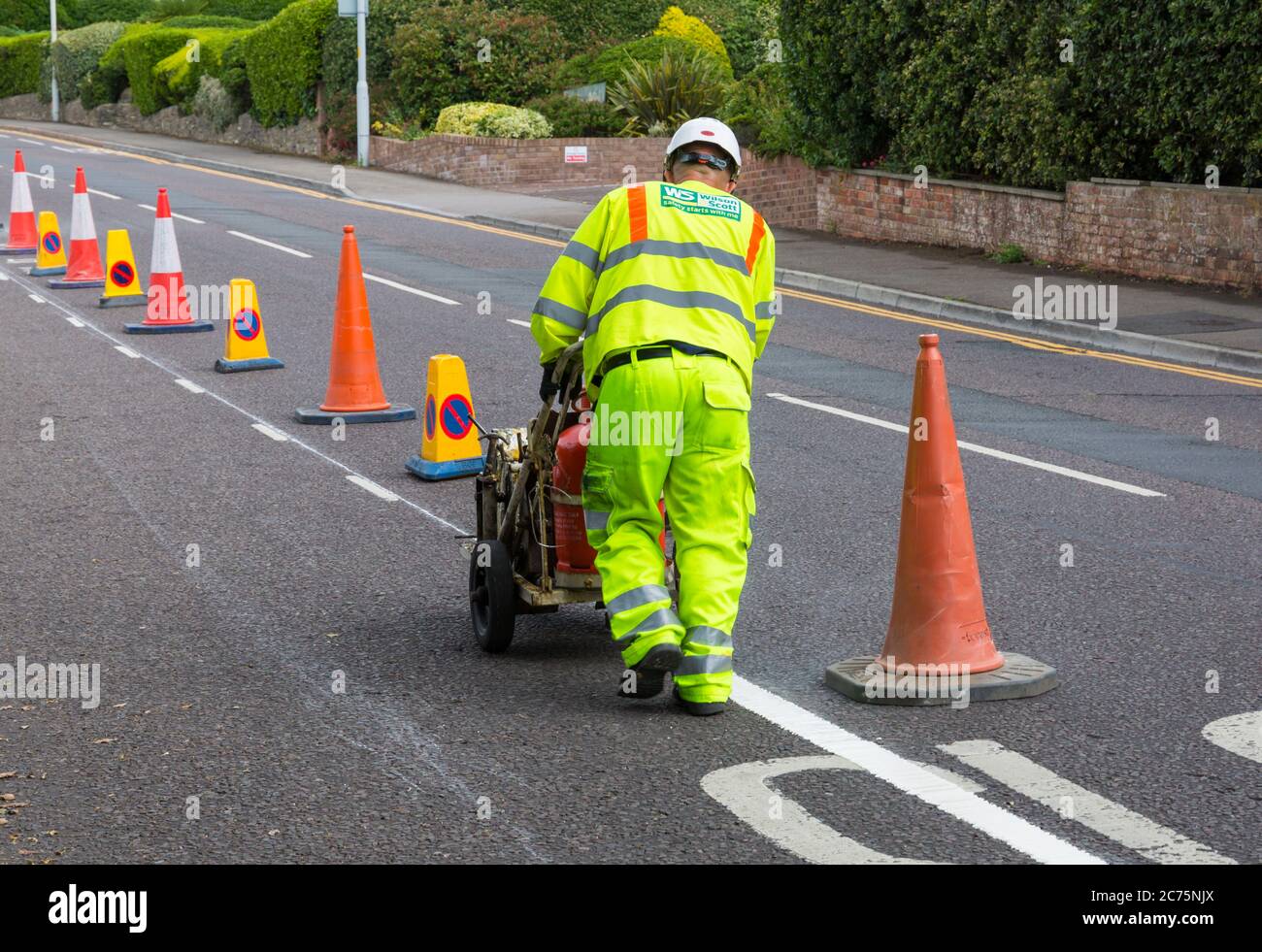 Painting white lines for new trial cycle lane at Evening Hill, Sandbanks, Poole, Dorset UK in July Stock Photo